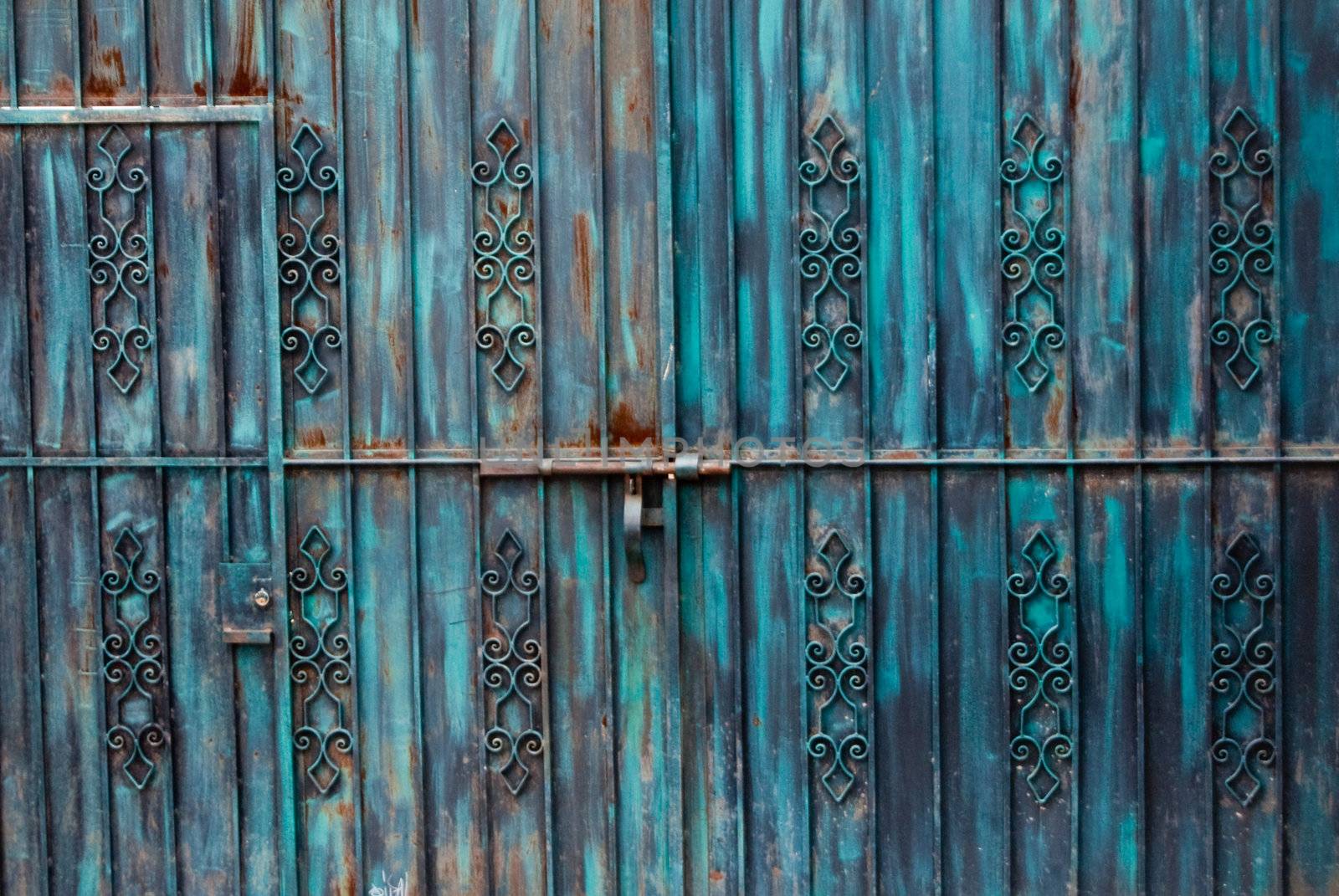 Rusted blue iron gateway with door
