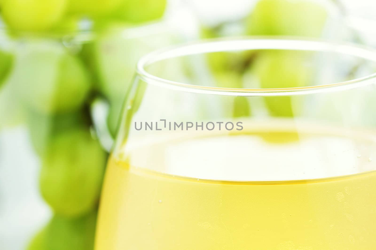 White grape juice in wine glasses with grapes in background. Water drops at 100%.