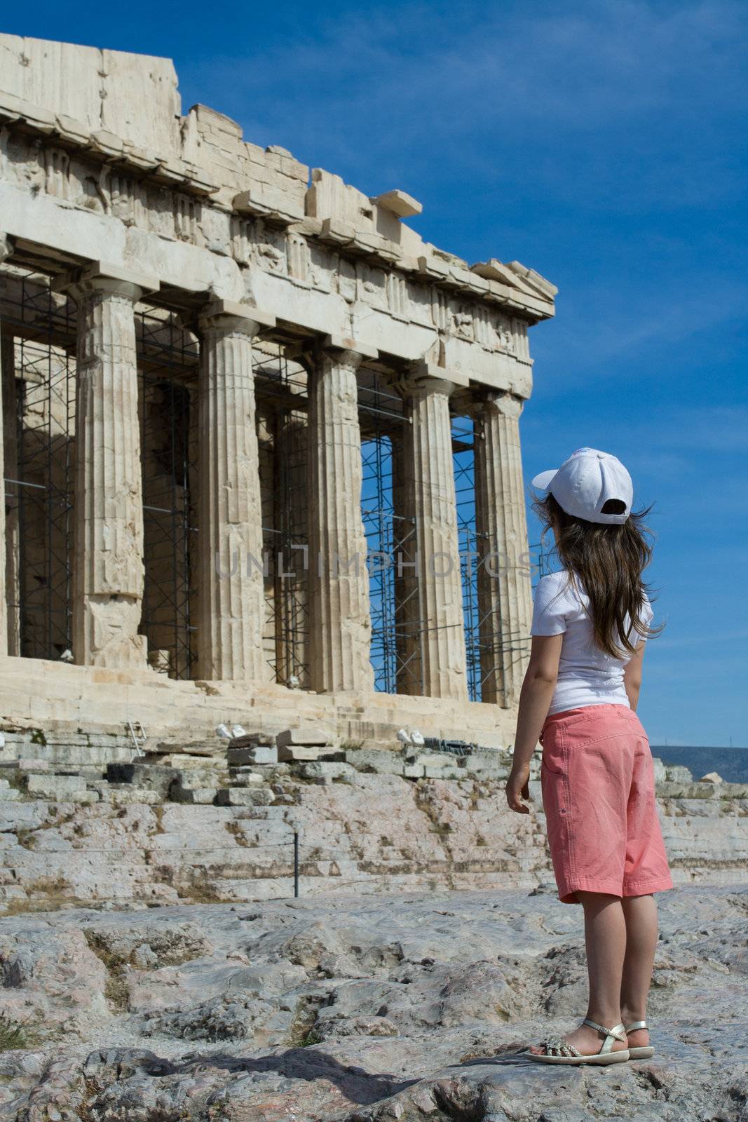 Child in front of Facade of ancient temple Parthenon in Acropolis Athens Greece on the blue sky background