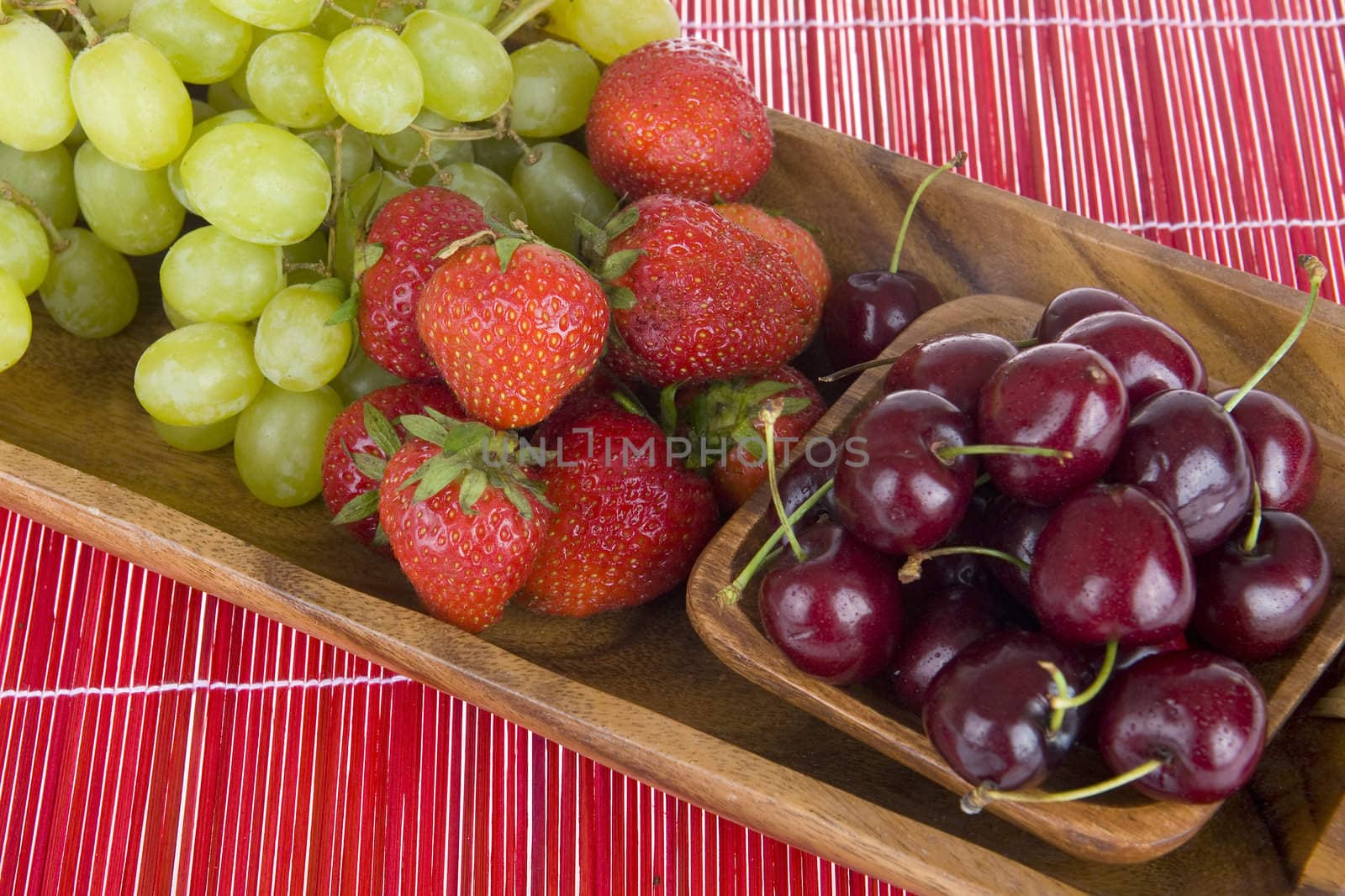 summerfruit in a wooden tray on a red carpet