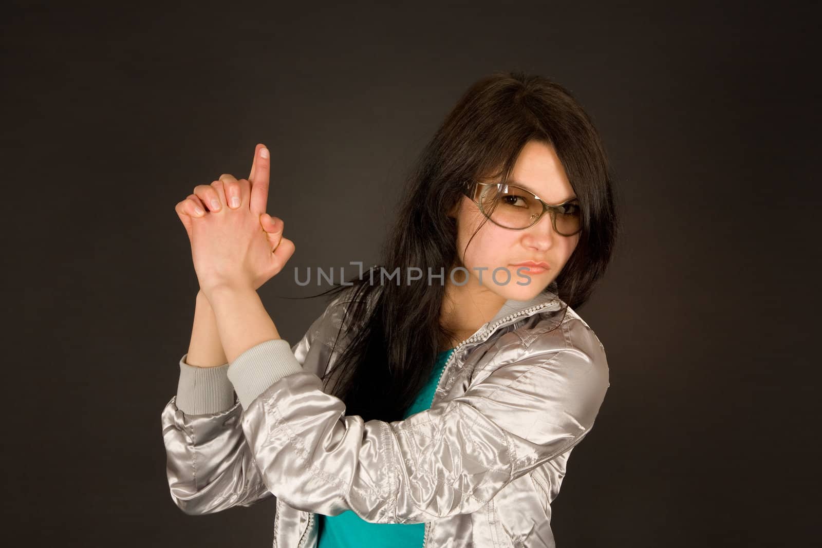 Fashion girl pointing her hand like a gun isolated on black 