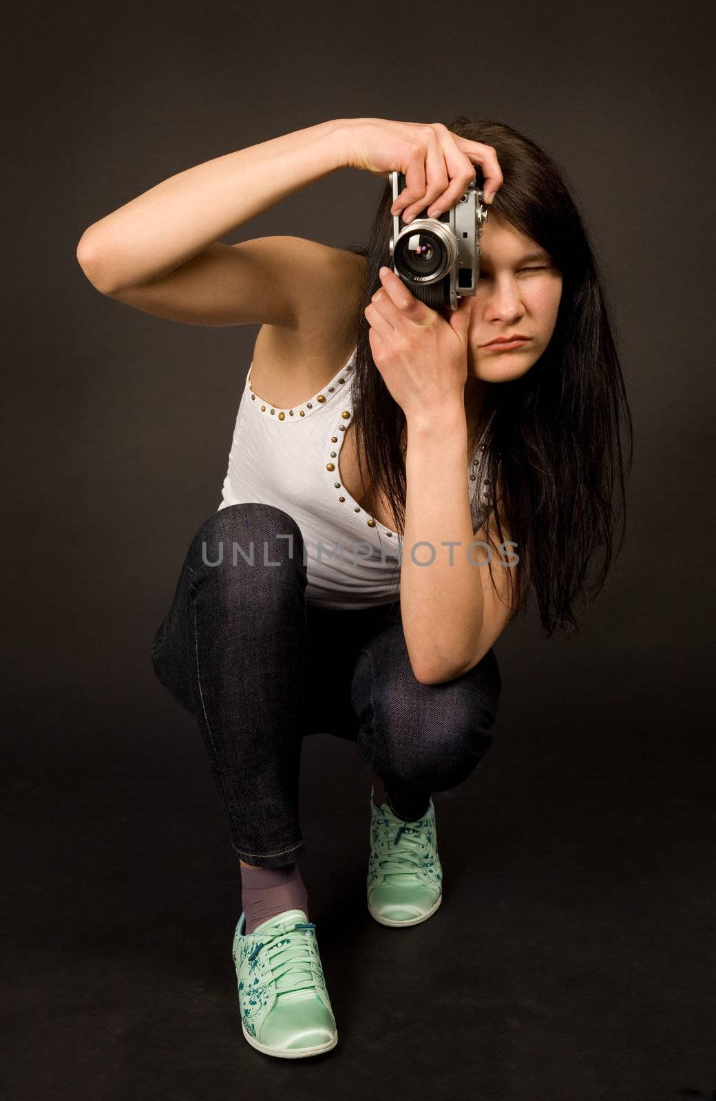 Young girl posing with old camera isolated on black background
