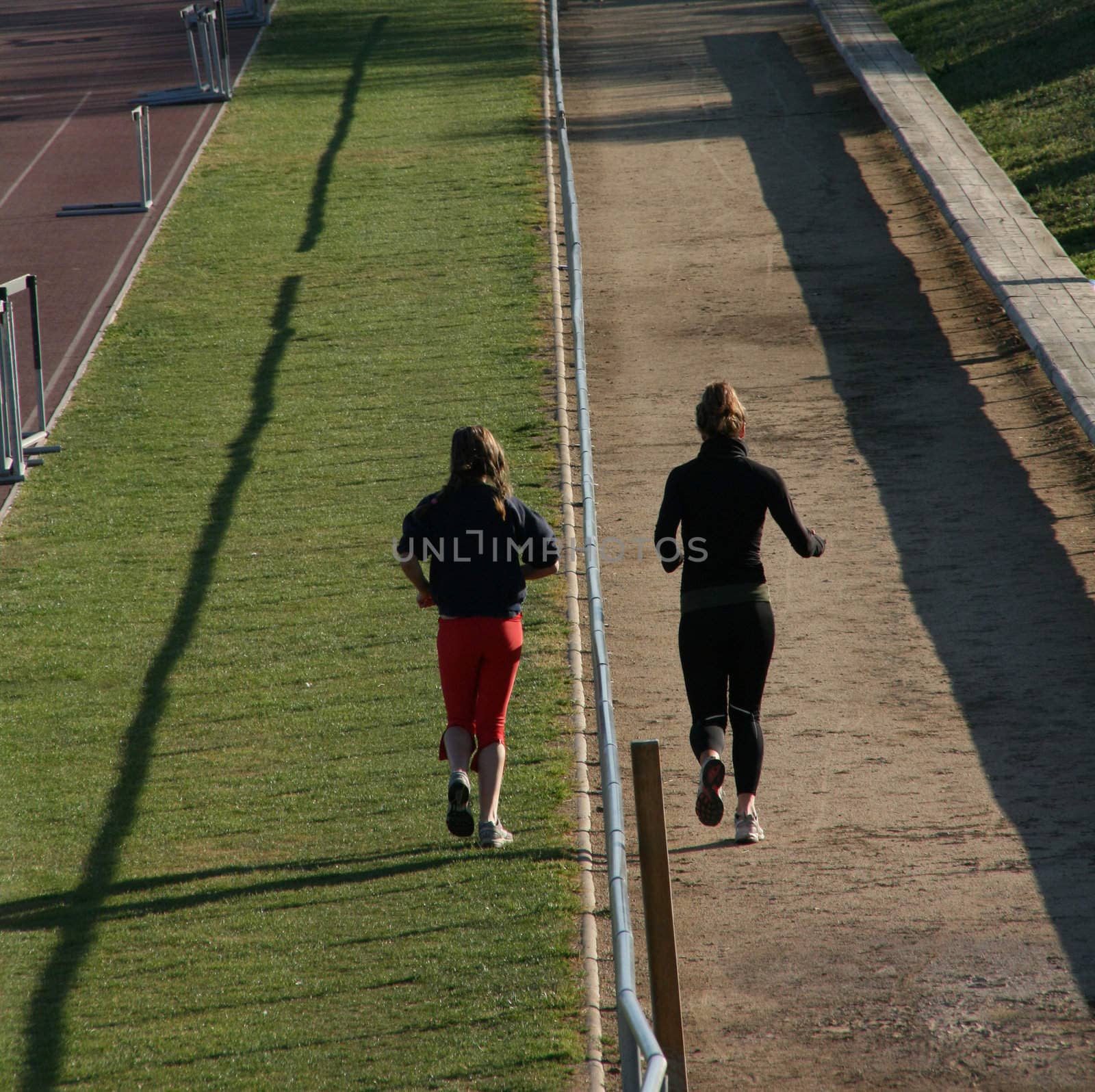 two girls jogging on a track and field stadium
