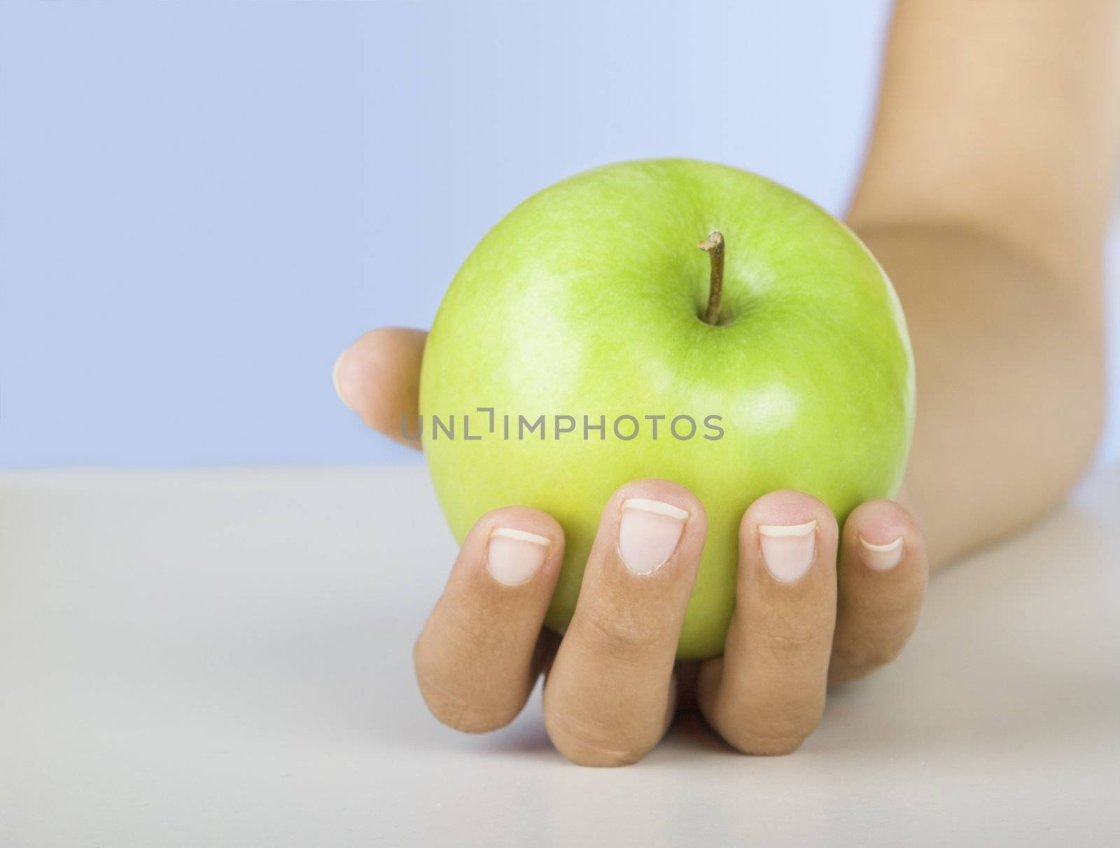 Close-up of a female hand holding a green apple