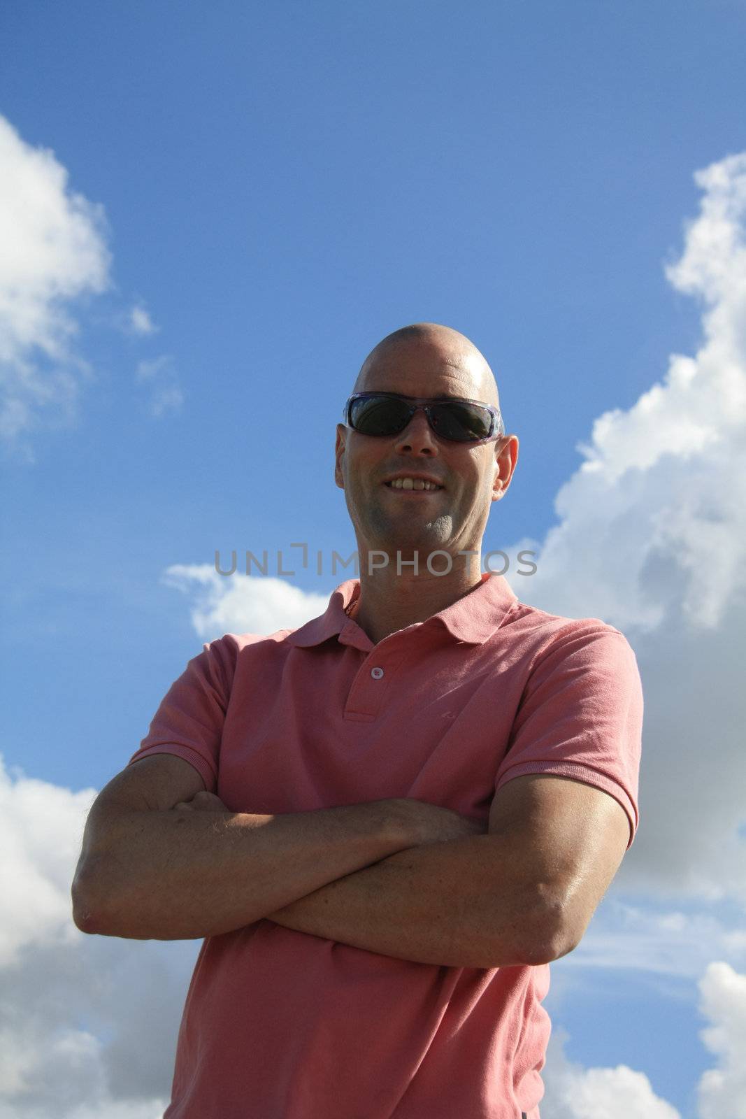 A bold man in pink shirt against clouded sky