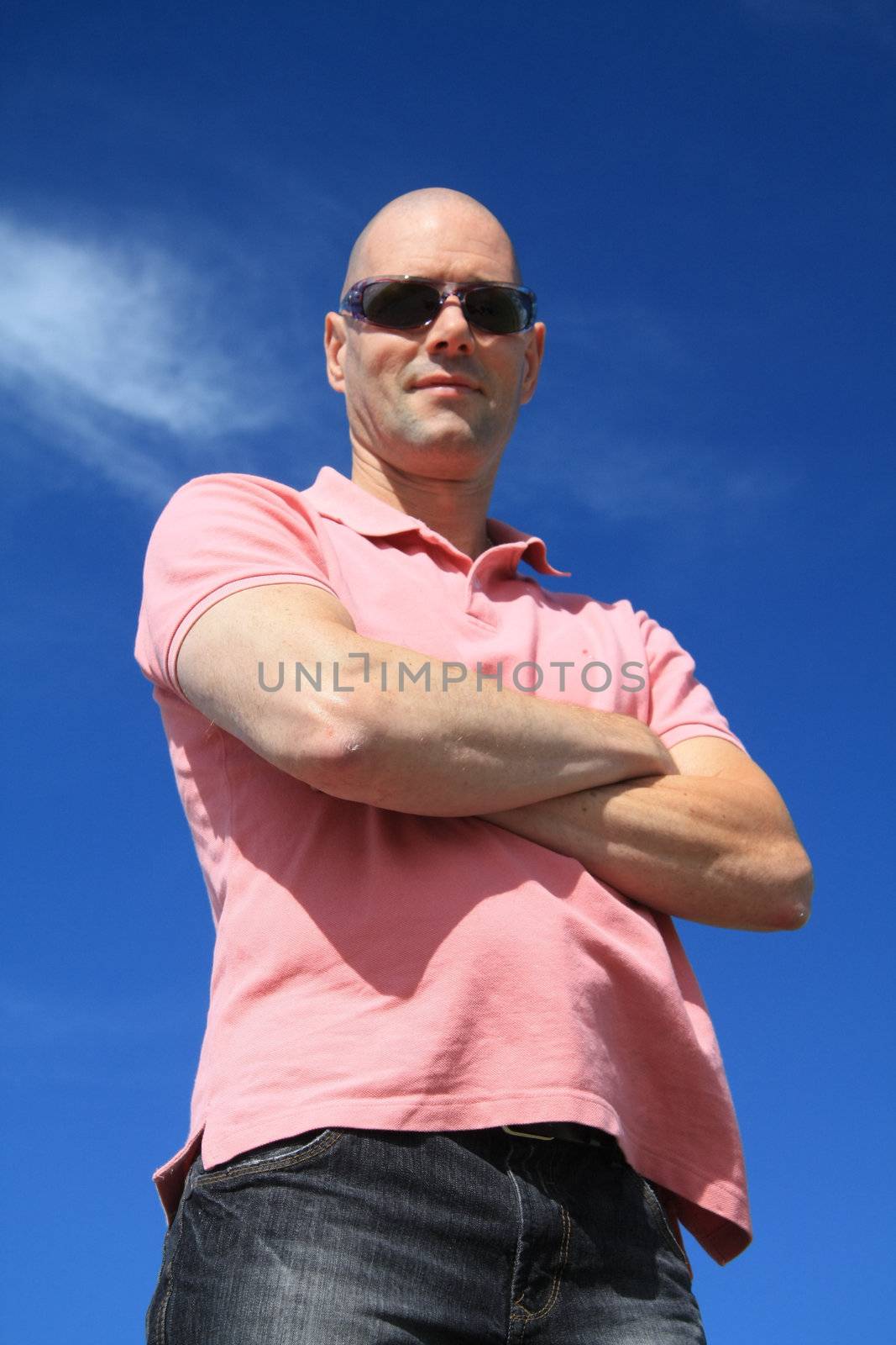 A bold man in pink shirt against clouded sky