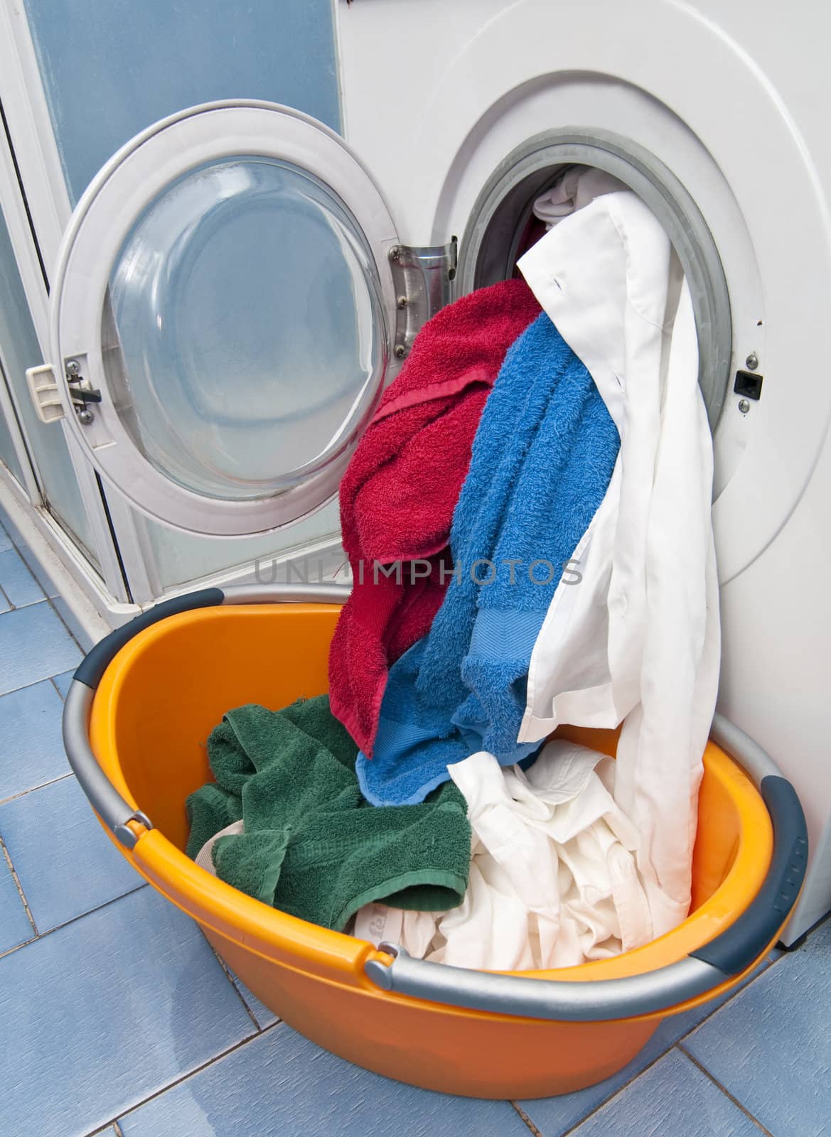 Open Washing machine with white, green, red and blue cloths
