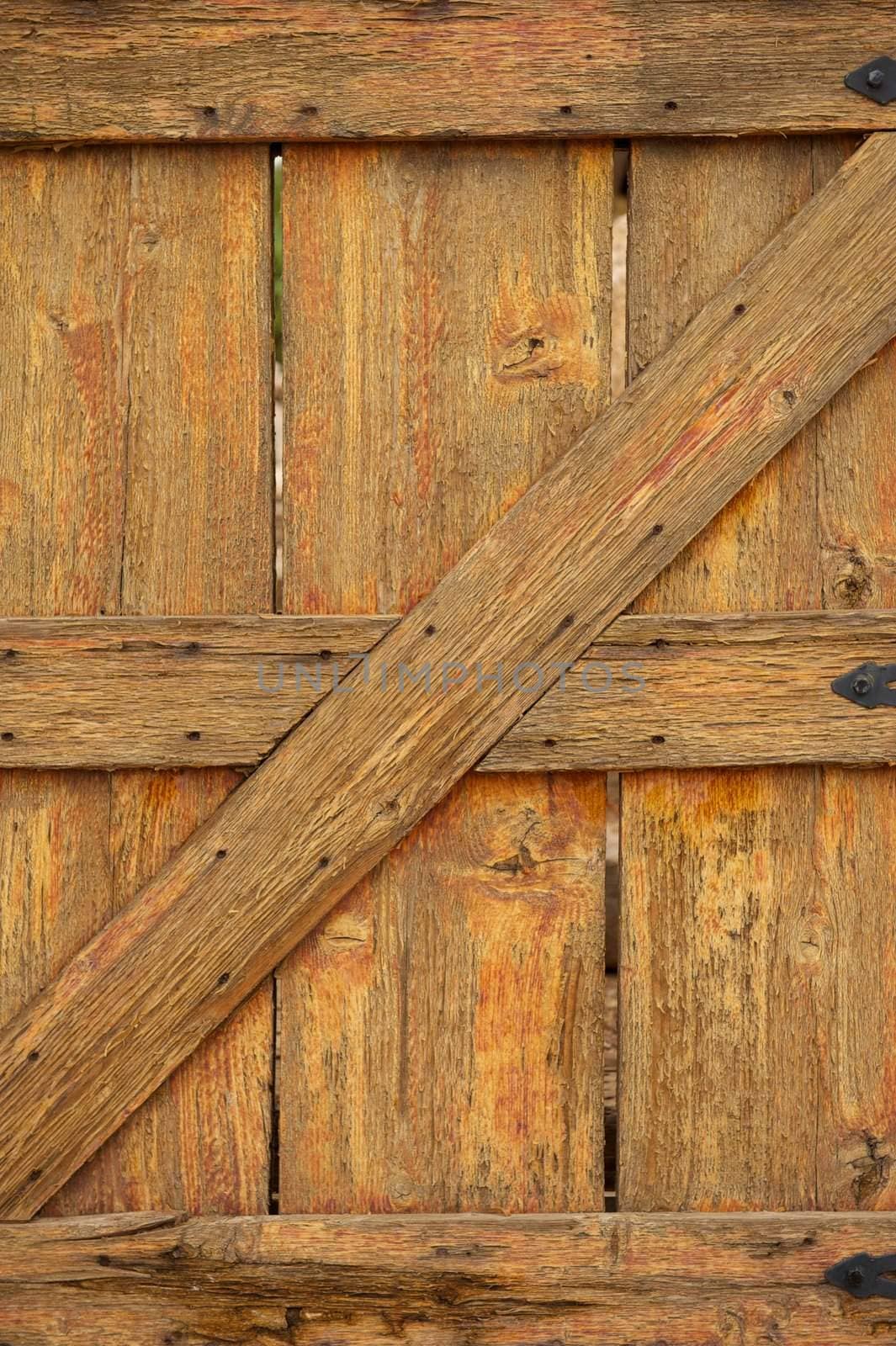 A worn and aged wooden gate with rusty nails and cracked paint
