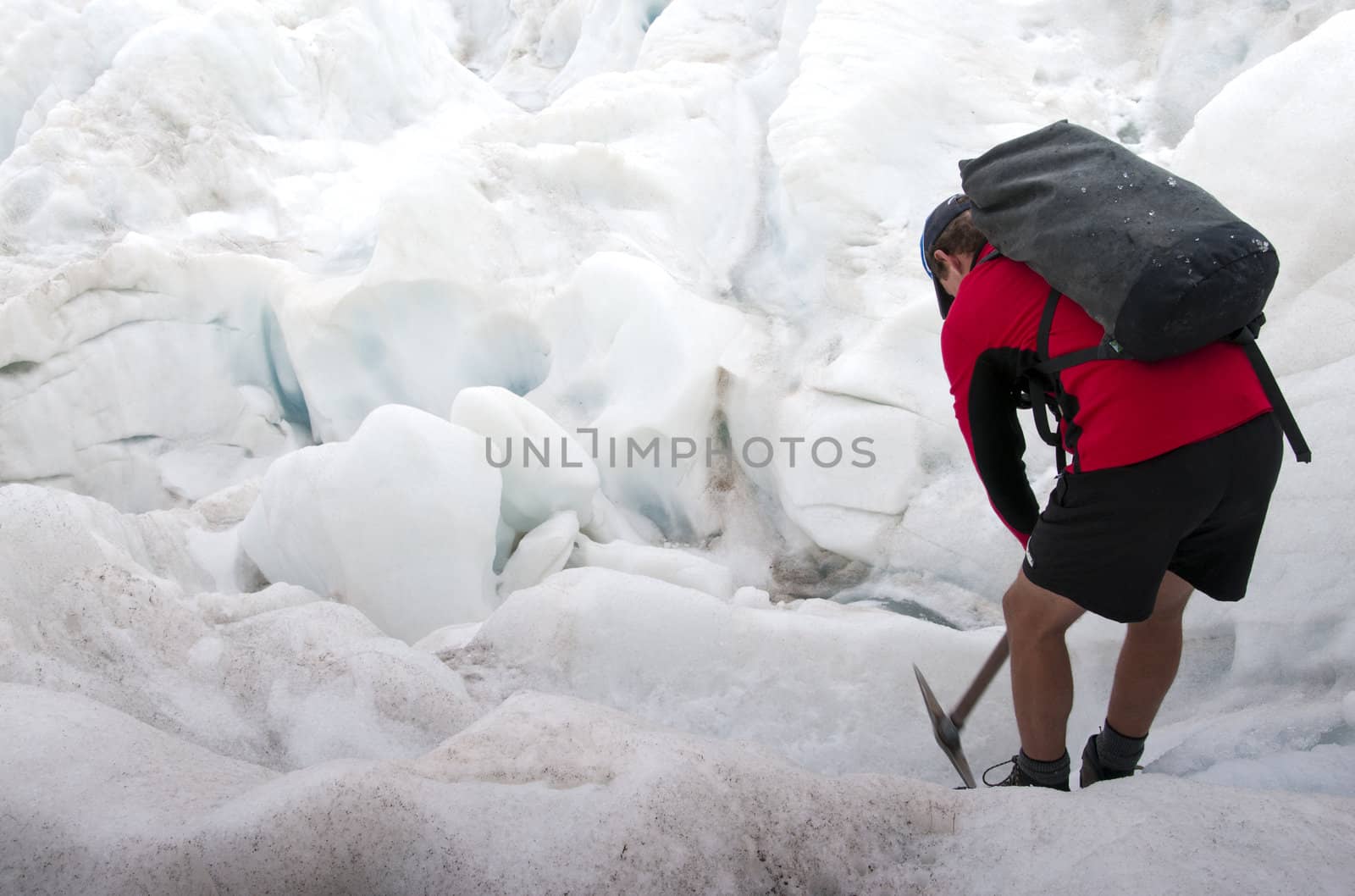 A hiker cutting his way through the ice on Fox Glacier in New Zealand. 