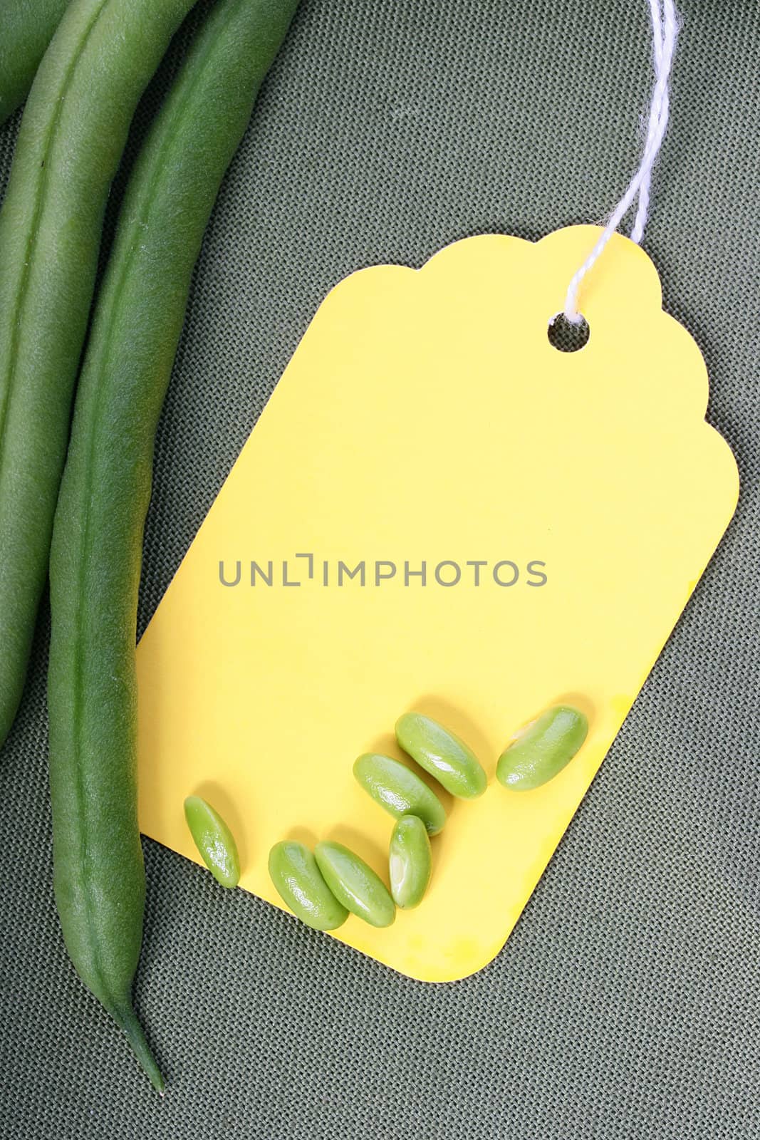 String bean in pods and beans on a napkin made of cloth with a label.