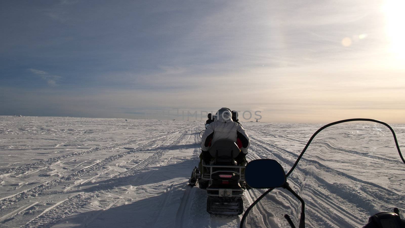 Snow scooters diving on a flat snowy plain