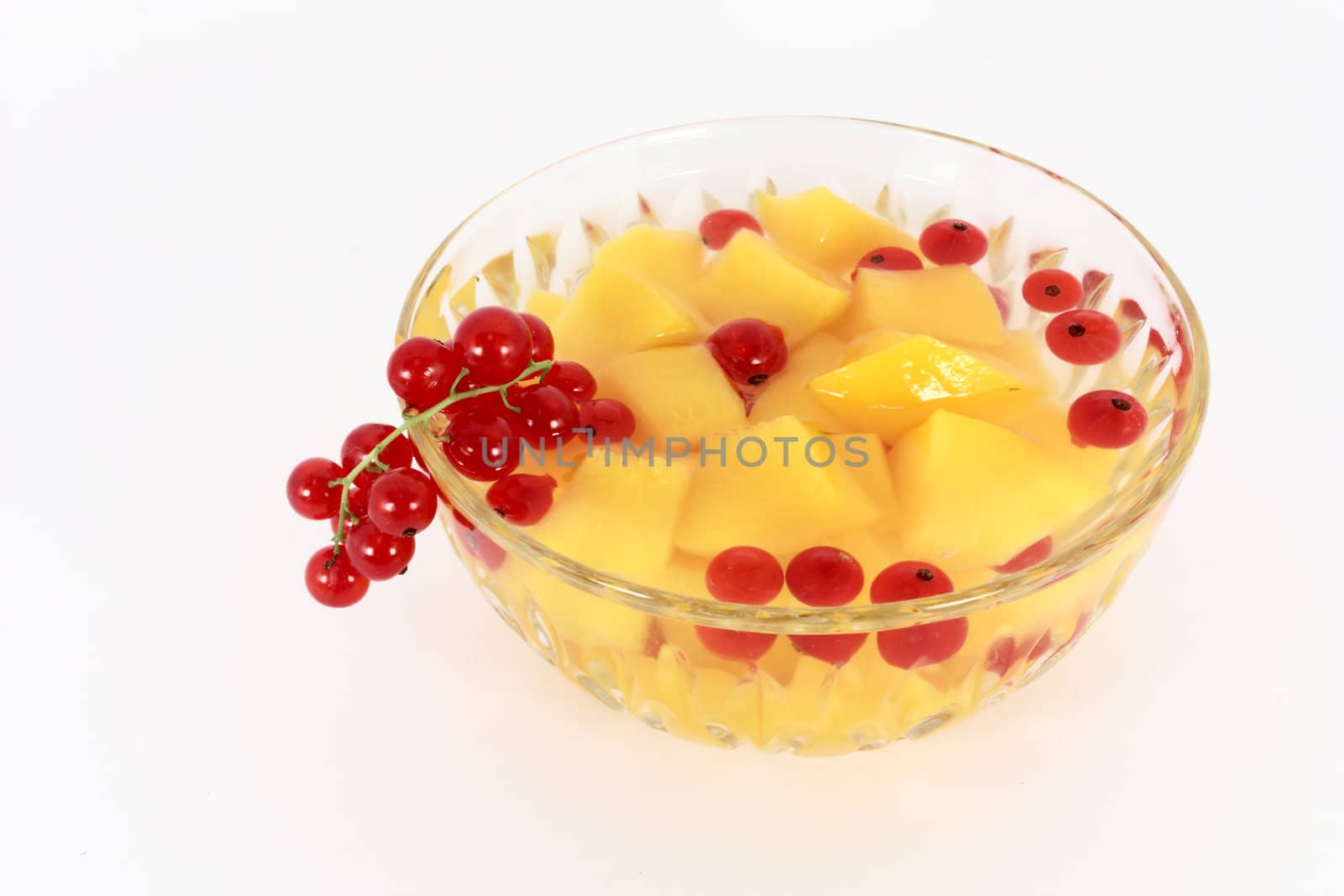 Peach compote with fresh red currants in glass bowl isolated on white