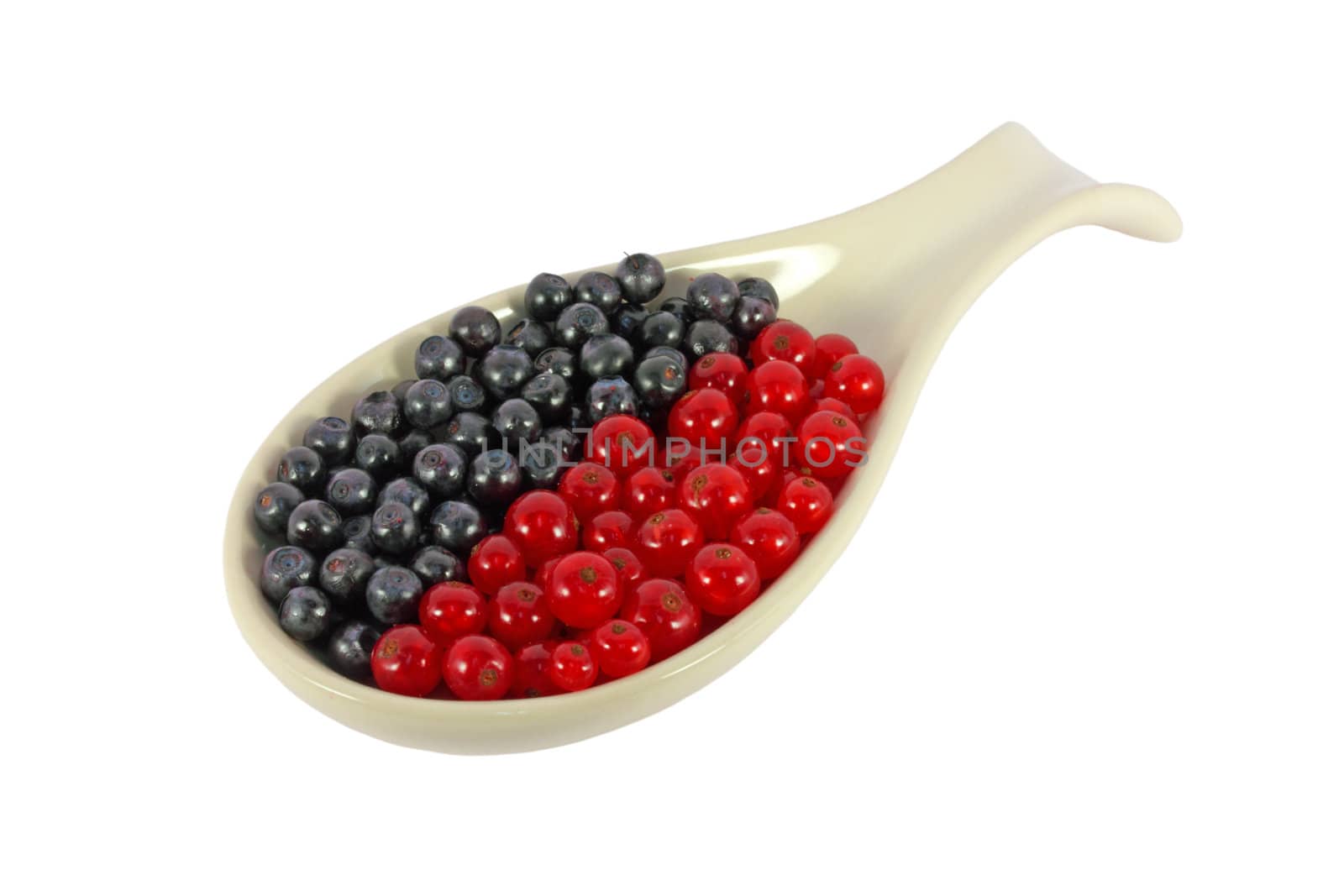 Blueberries and currants in a spoon isolated on white