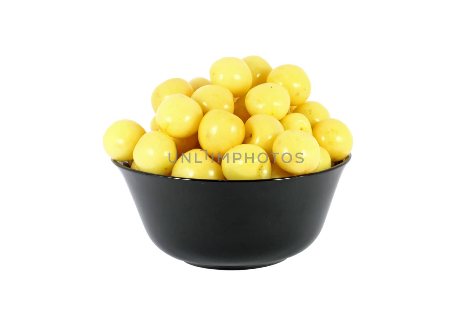 Black bowl full of yellow cherries isolated on white
