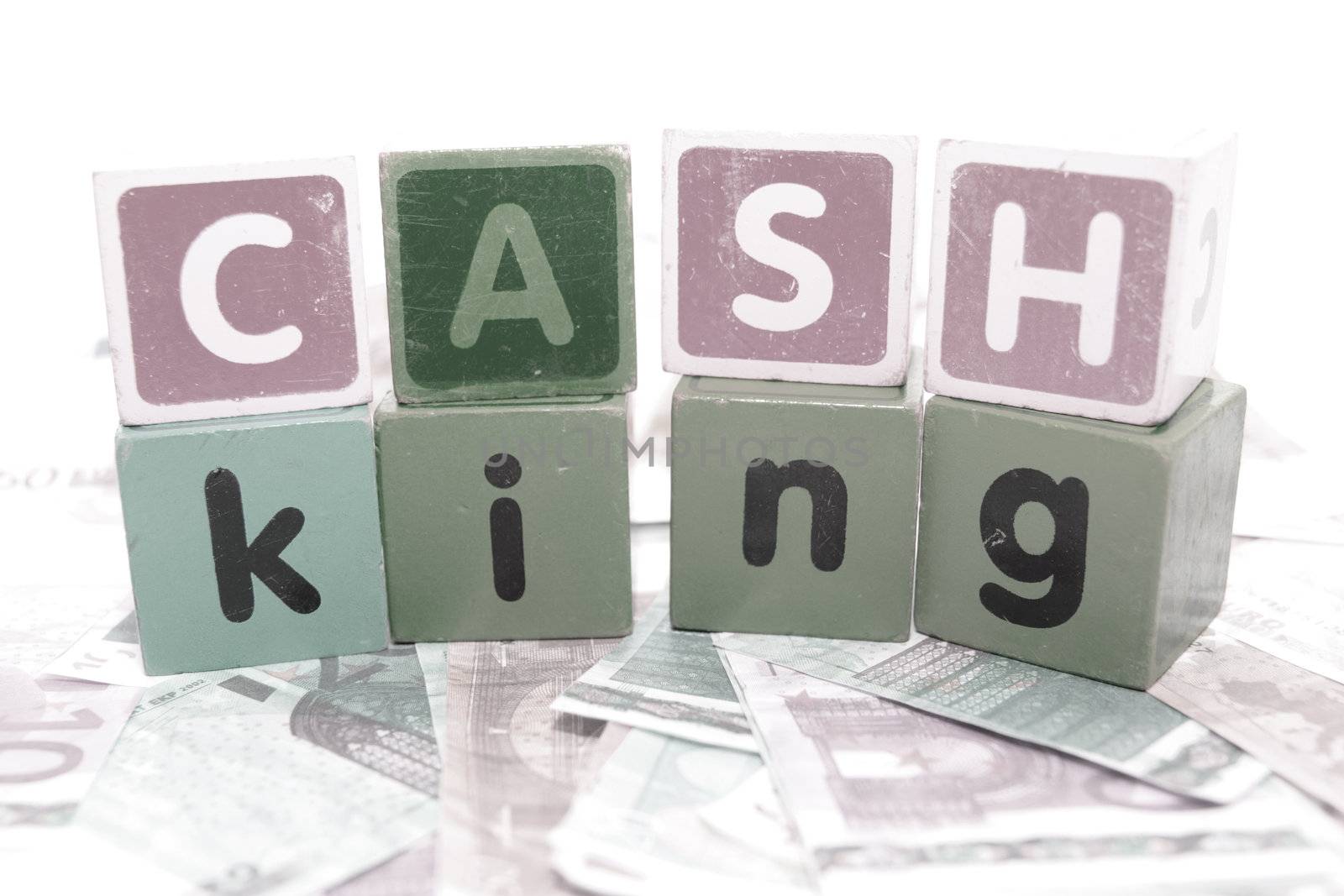 assorted childrens toy letter building blocks against a white background on money that spell cash king
