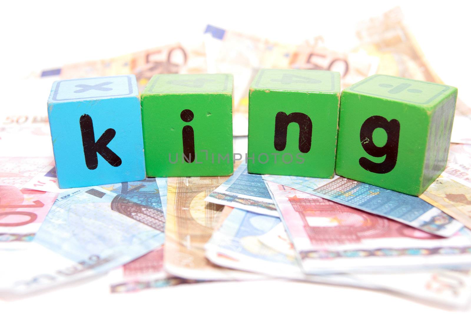 assorted childrens toy letter building blocks against a white background on money that spell king