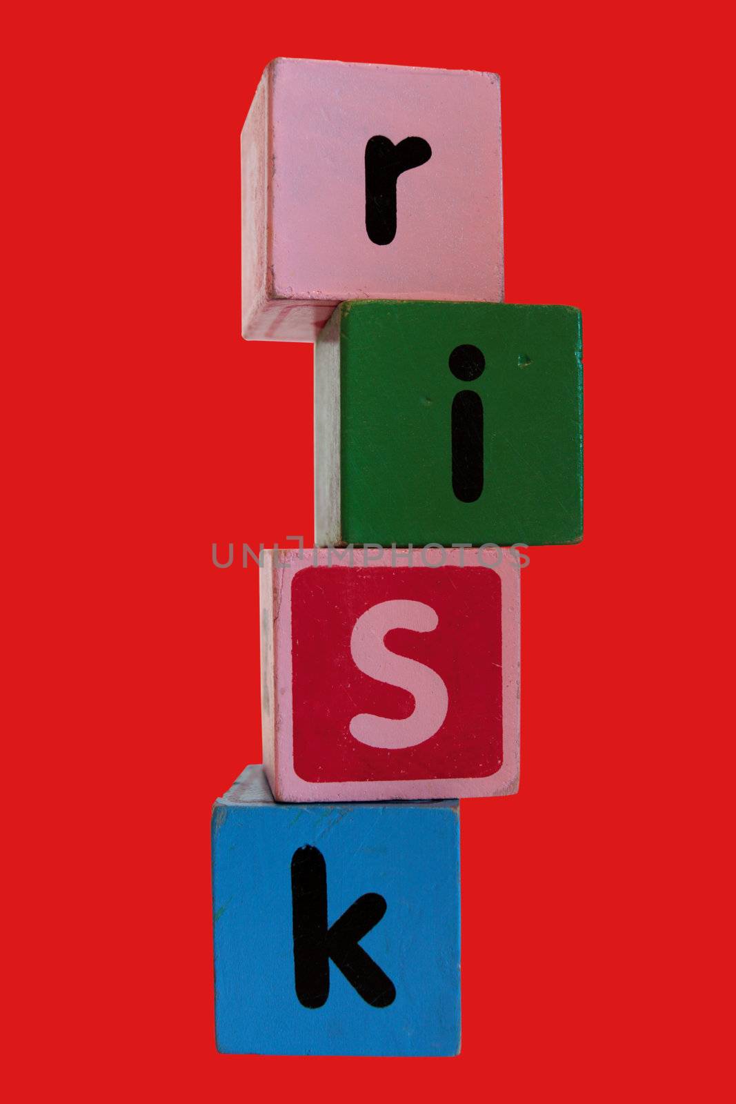 assorted childrens toy letter building blocks against a red background that spell risk