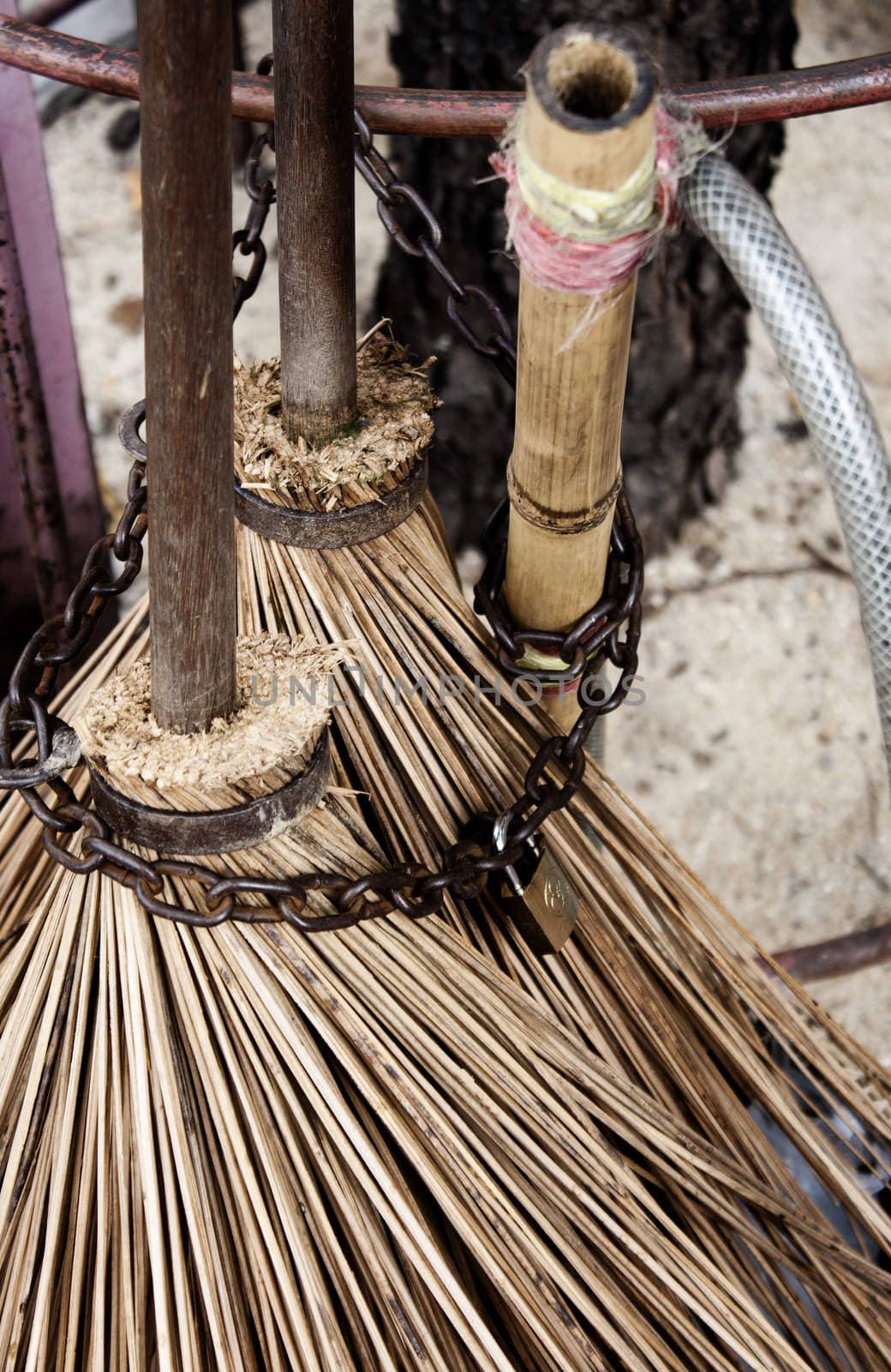 Two straw brooms attached by a chain on a pavement in the city of Bangkok, Thailand 