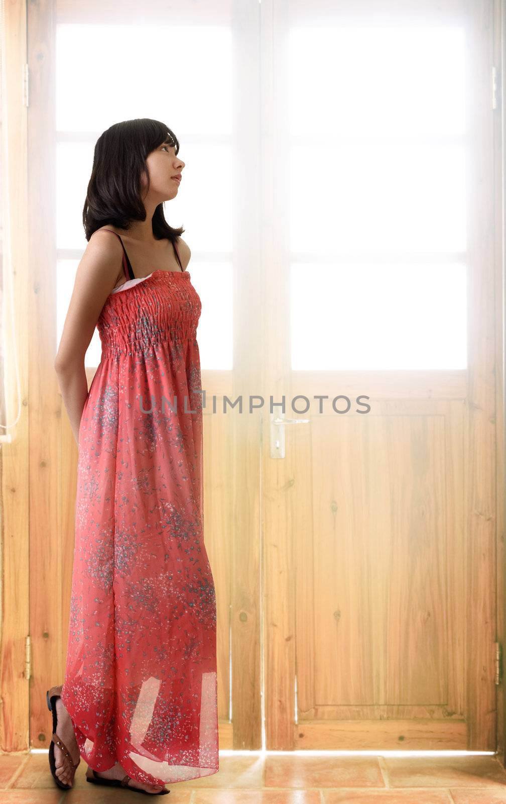 Oriental girl thinking and standing in front of door with light.