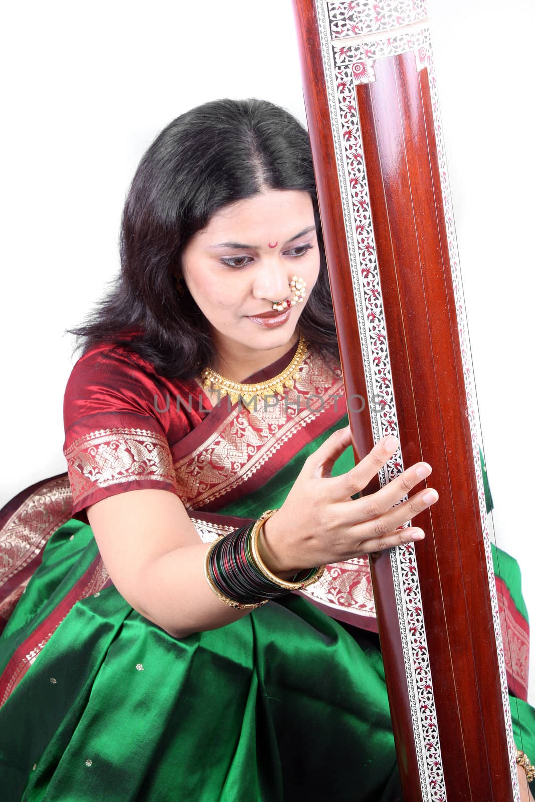 An Indian classical singer with the tanpura instrument, in a traditional attire. (Focus on the hand playing the instrument)