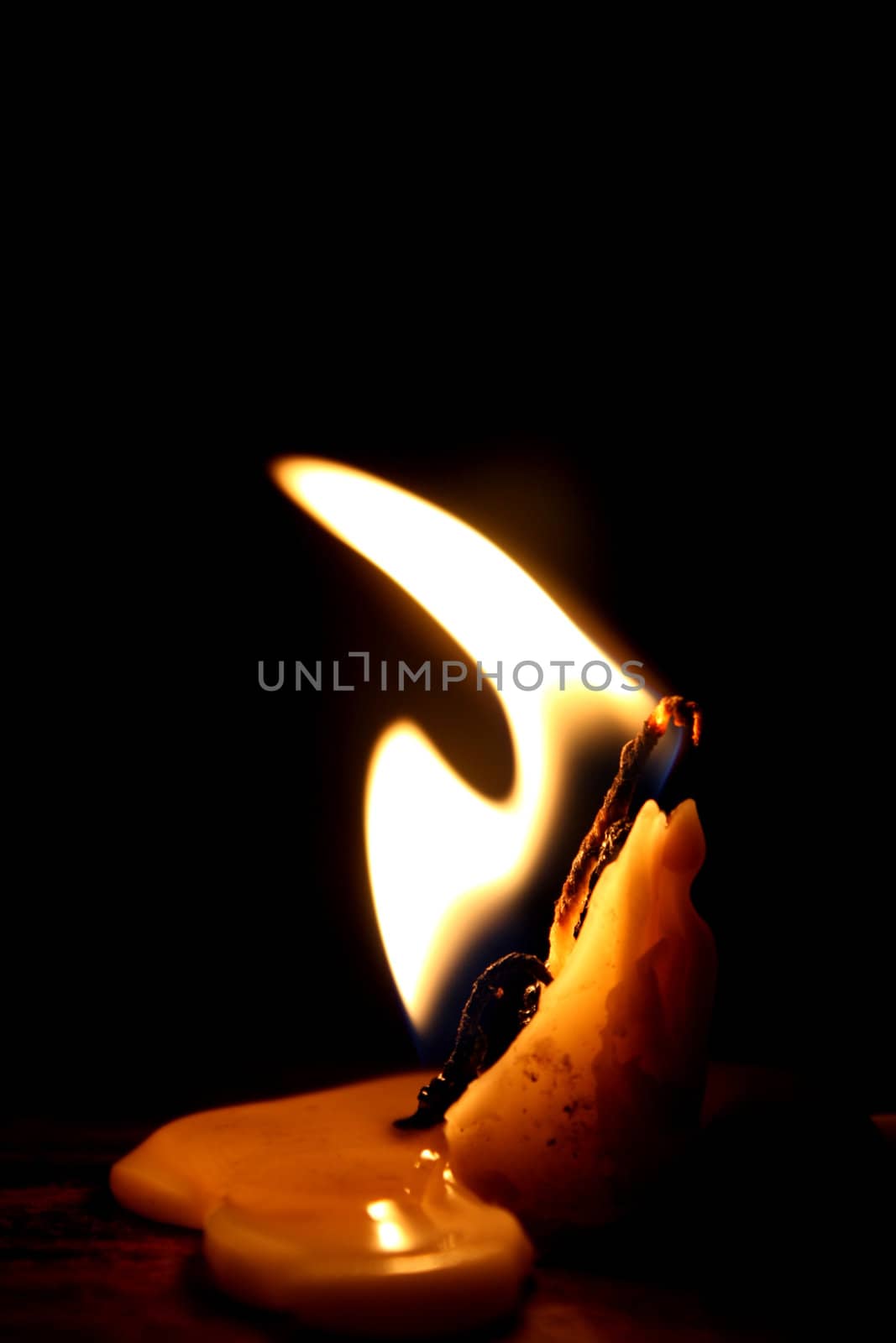 A wax candle burning in an abstract shape.