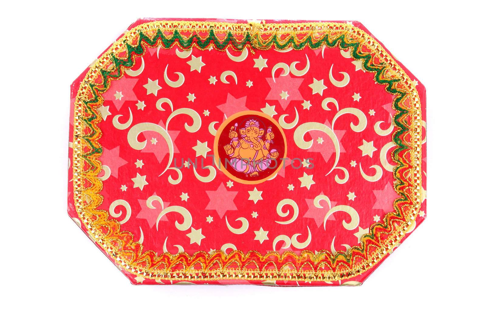 An Indian festival giftbox having a traditional design with Lord Ganesha at the center, isolated on a white background.