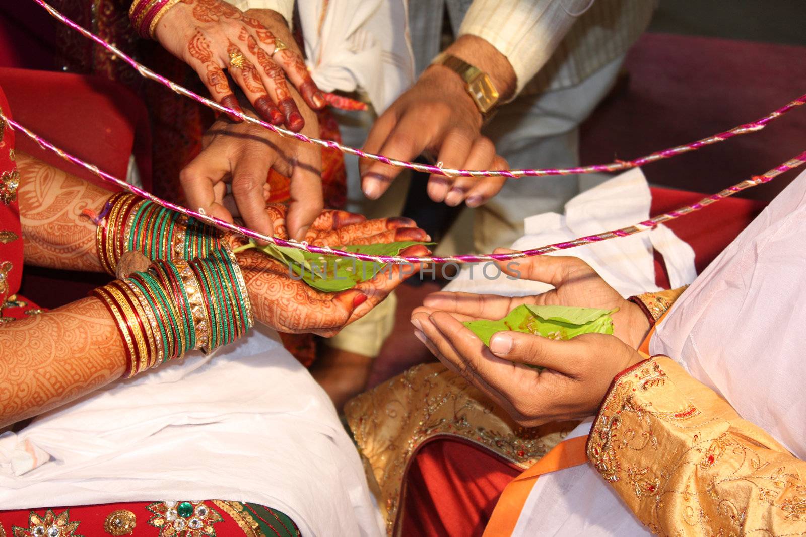 The hands of the groom and the bride performing an ancient ritual in a traditional hindu wedding.