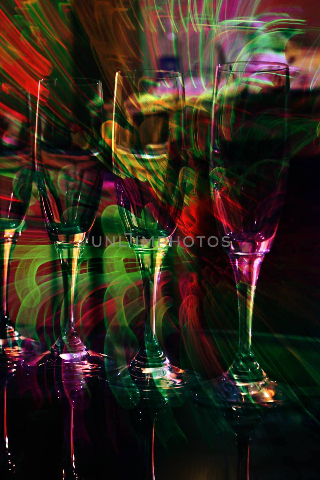 An abstract long exposure view of champagne glasses in colorful lights of a disco.