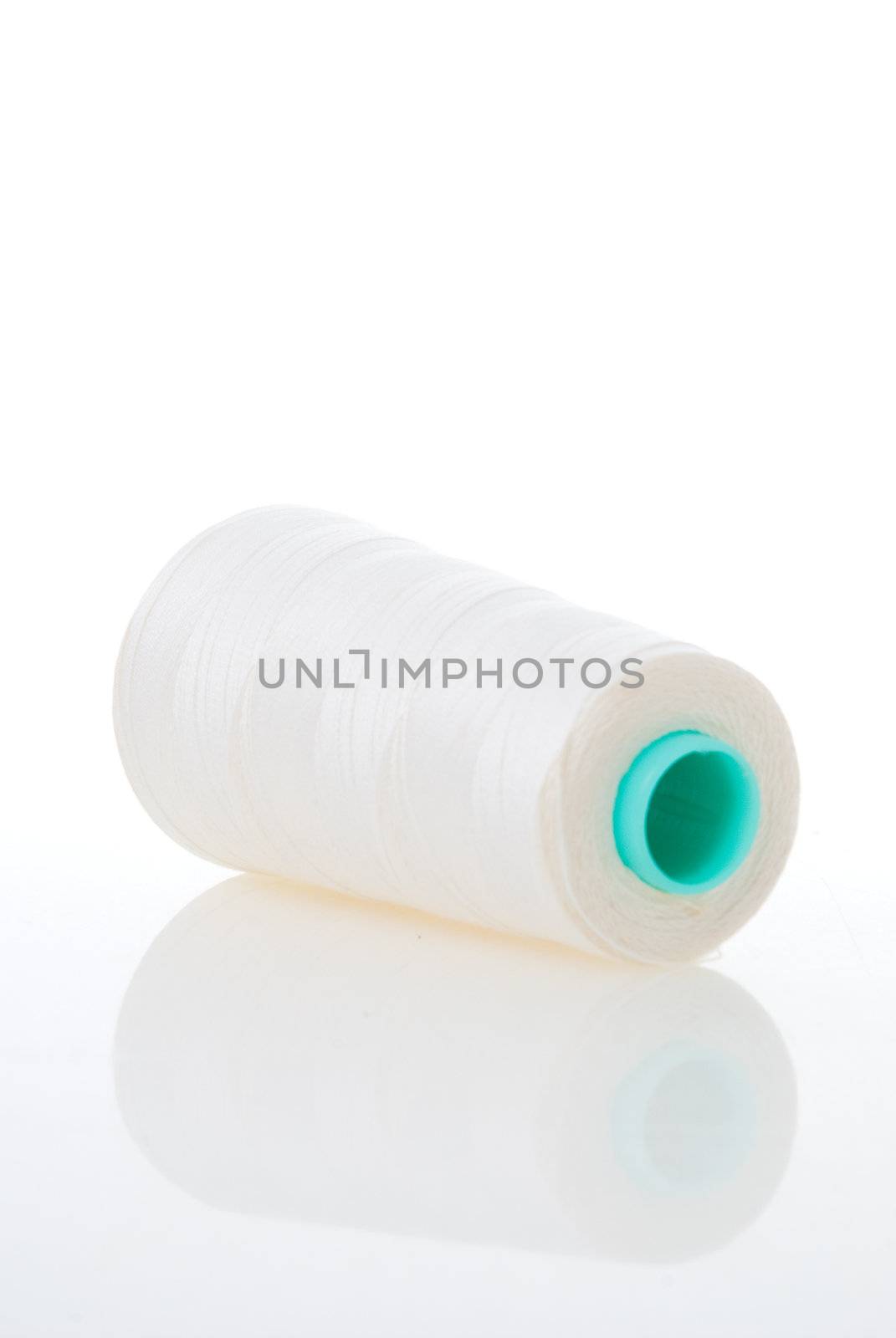 Bobbin of white thread isolated on white background with reflection.