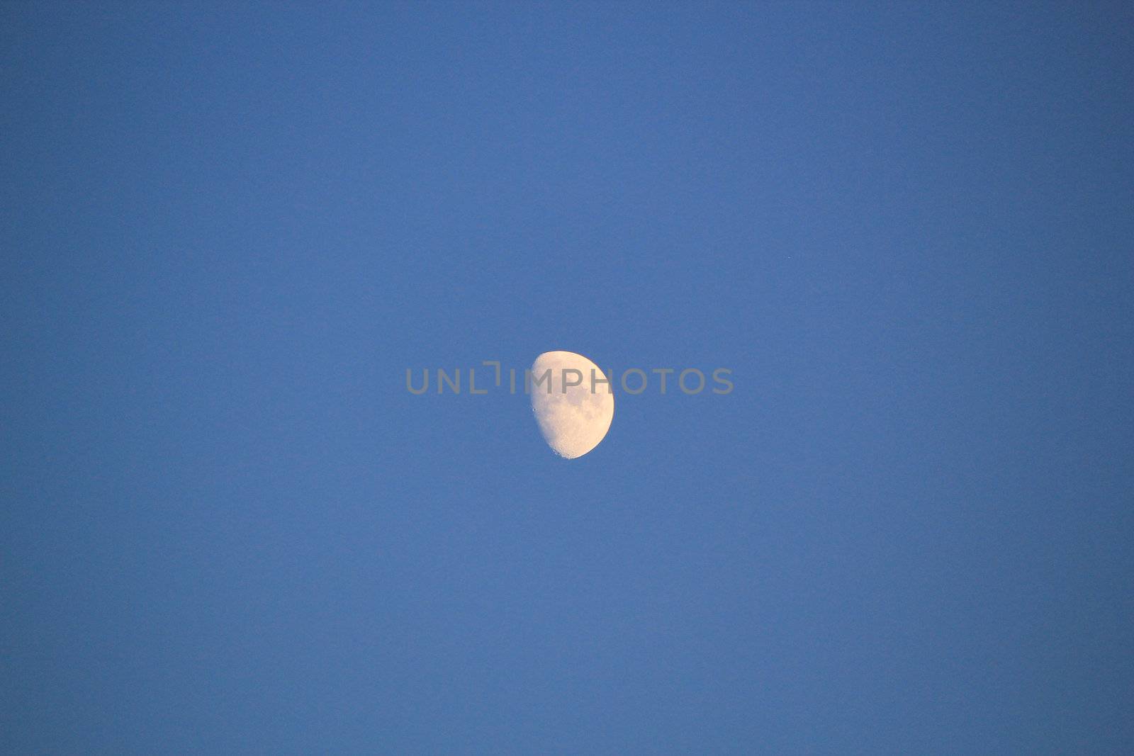 Partial moon in a deep blue sky