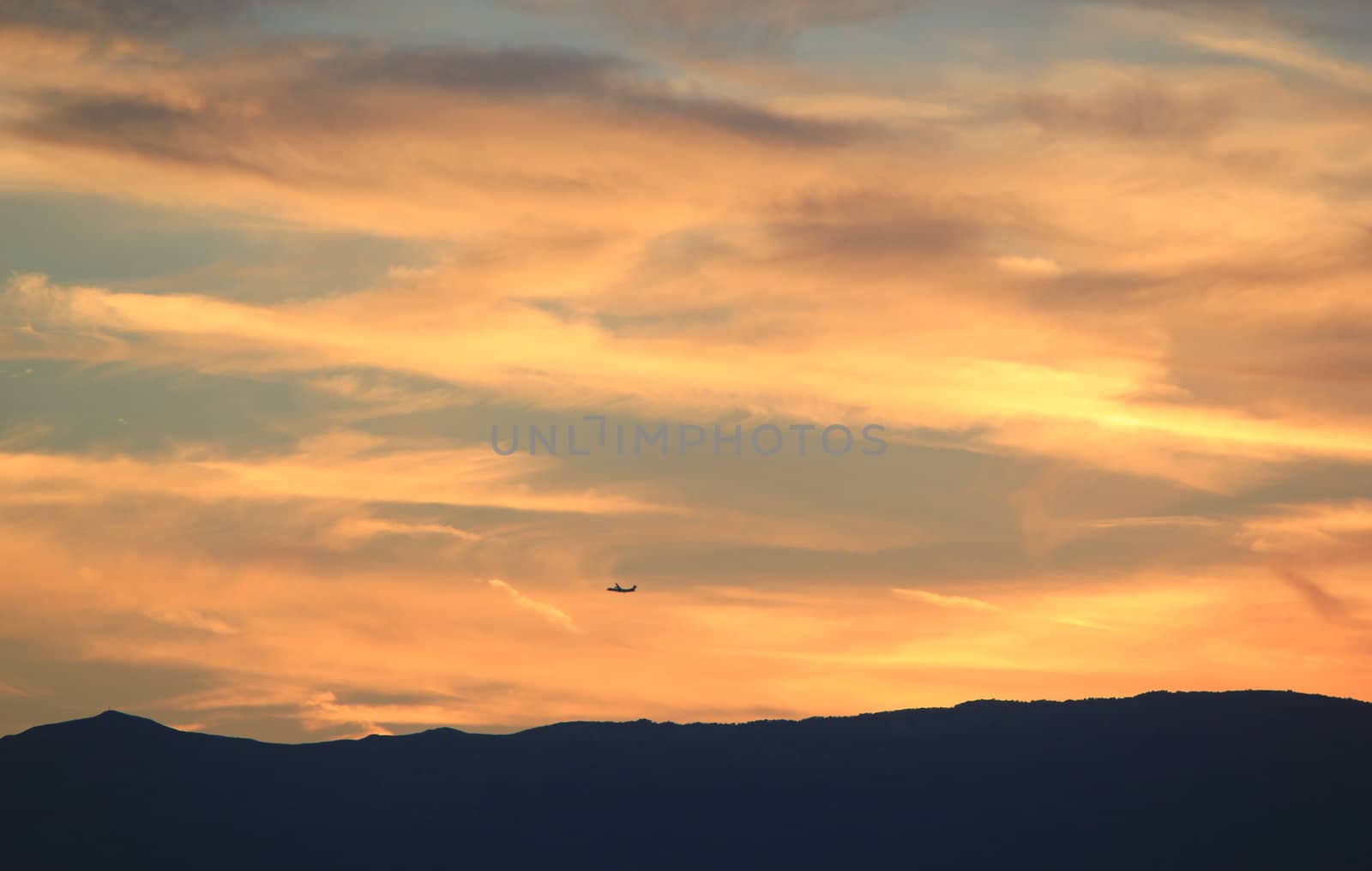 Plane flying upon mountain and clouds by sunset by Elenaphotos21