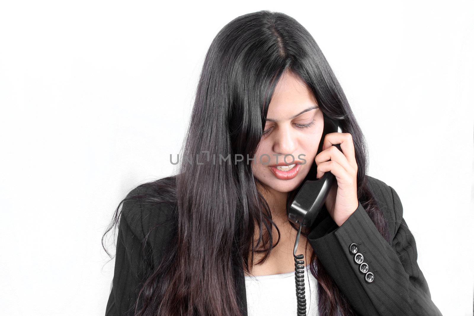 An Indian businesswoman talking on the telephone, on white studio background.