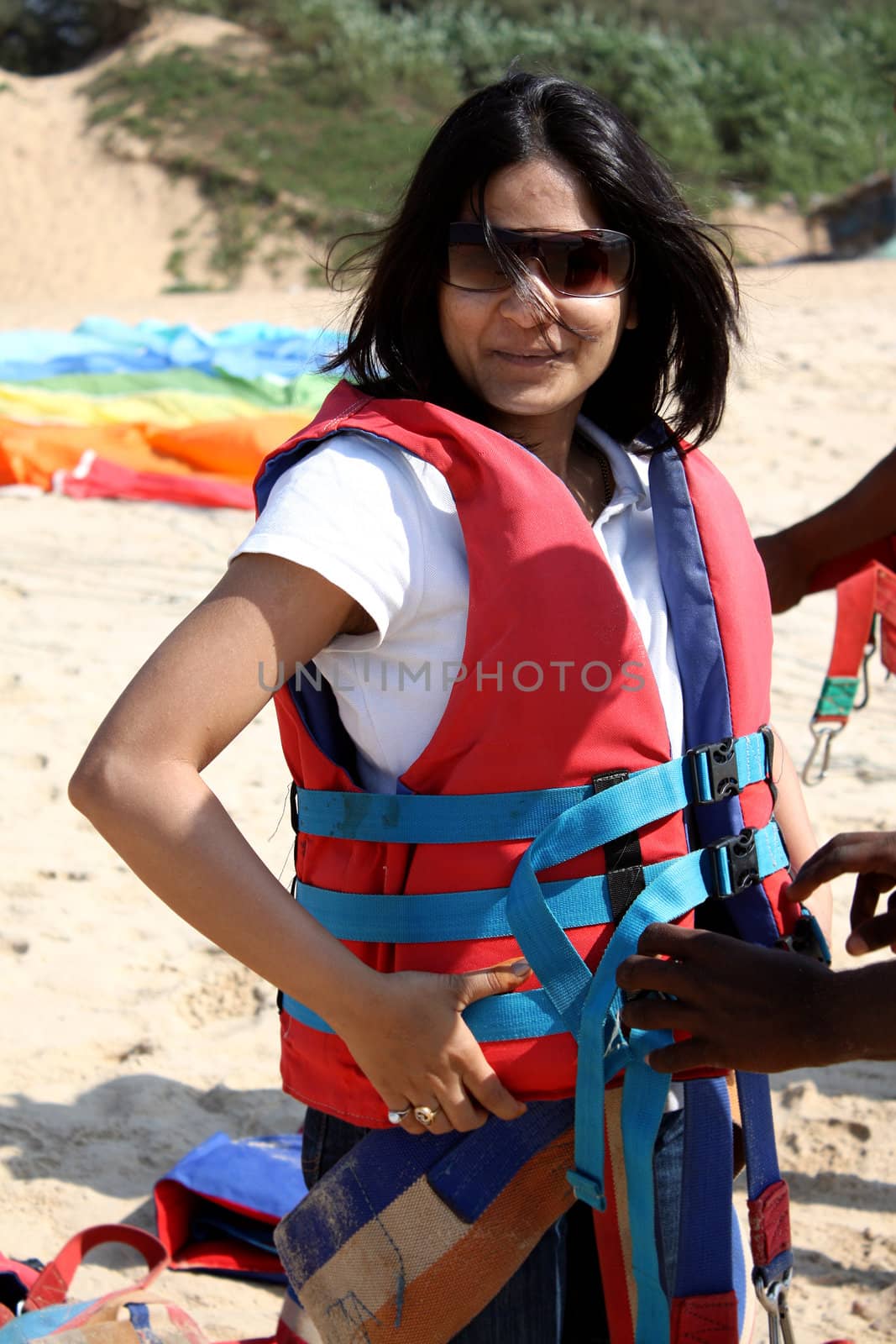 A girl getting ready wearing the safety equipment for parasailing.