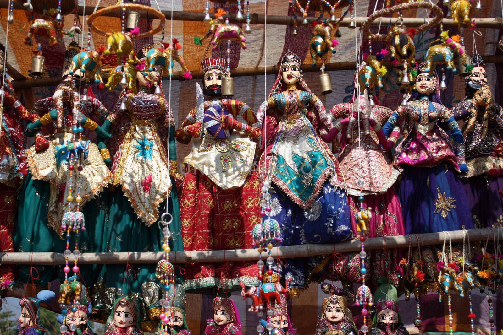 A view of ethnic decorative item consisting of colorful bead and elephants made of colorful cloth, on the backdrop of traditional Indian Rajasthani puppets.