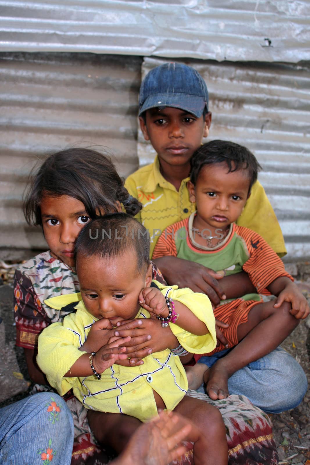 Poor sick chilren sitting on the sides of a street, in India.