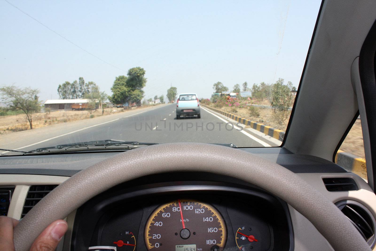 A view from the inside of a car speeding on a highway. Focus on Speedometer.