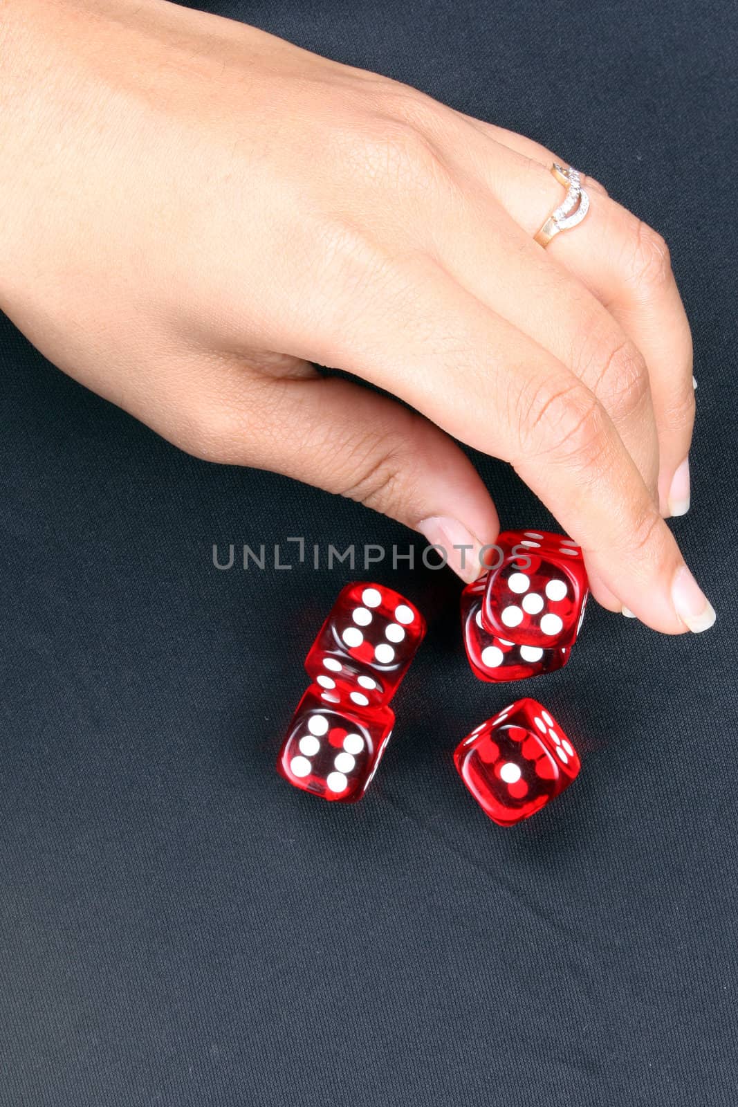 A hand picking up red gambling dices kept on a black fabric.