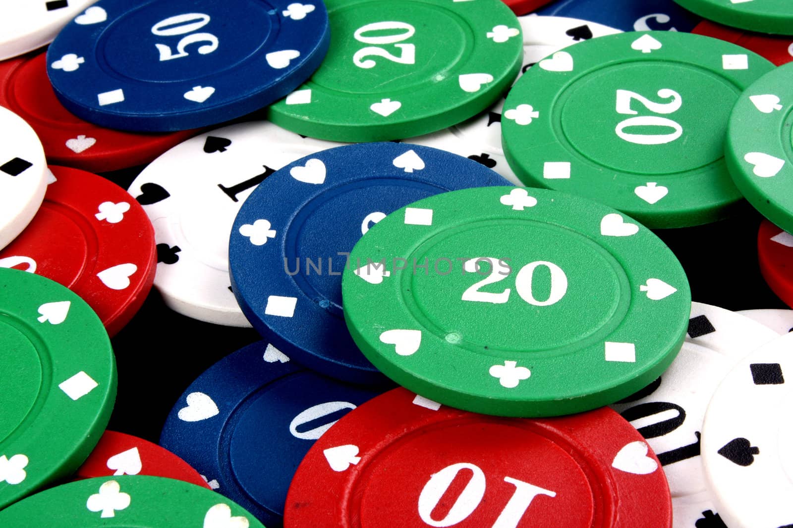 A background with a view of a green gambling chip of 20 lying on a heap of other colorfup chips.