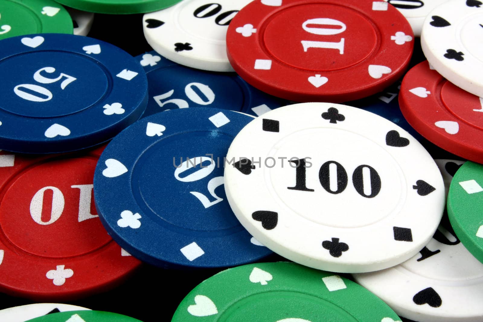 A background with a view of a white gambling chip of 100 lying on a heap of other colorfup chips.