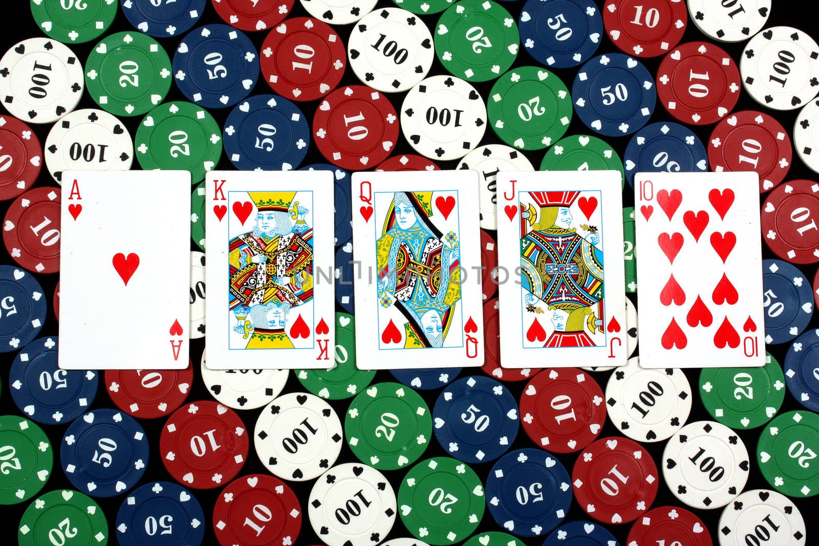A poker hand of royal flush on the background of casino chips.