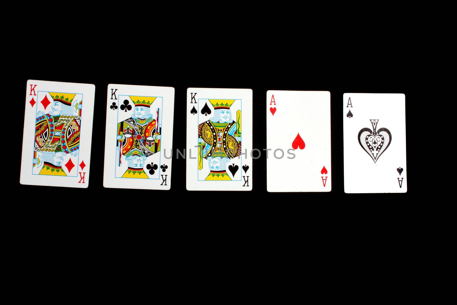 A poker hand of 'full house' consisting of two aces and three kings, on black background.