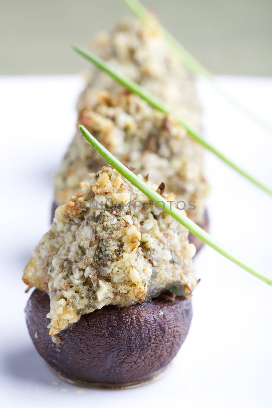 Button mushrooms stuffed with chopped nuts herbs and spices topped with a chive.