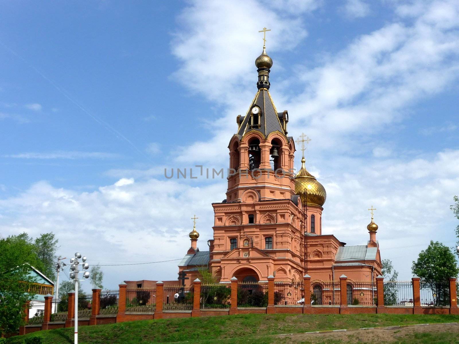 Red urban church on a background of blue sky with clouds