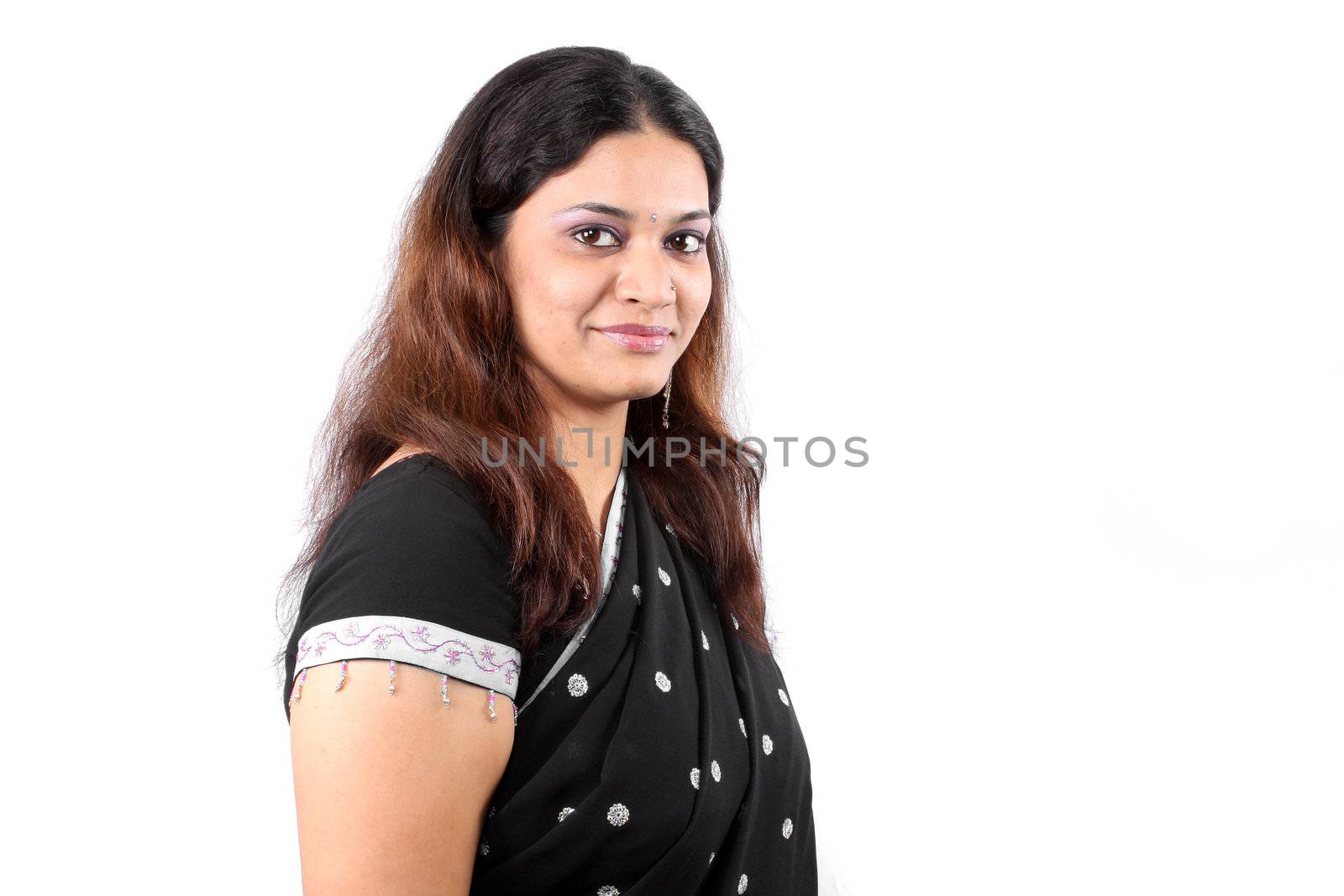 A portrait of a young Indian woman wearing a traditional black sari, on white studio background.