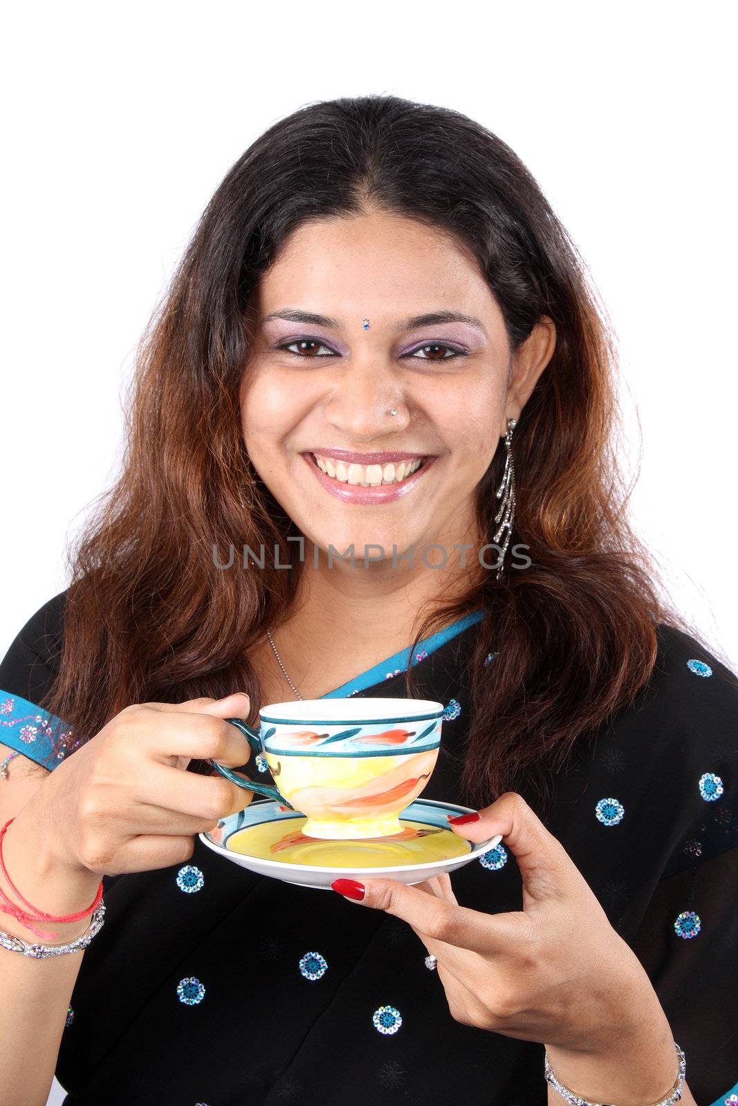 A portrait of a smiling Indian woman having tea, on white studio background.