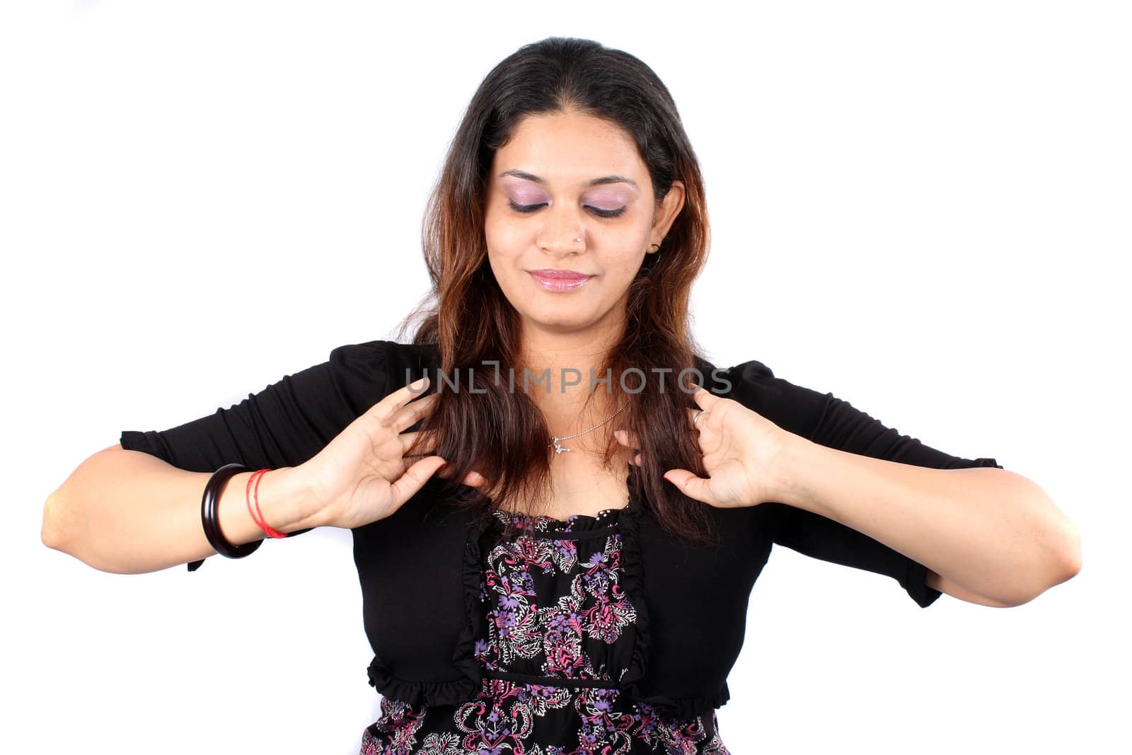A cute Indian lady styling her hair, on white studio background.