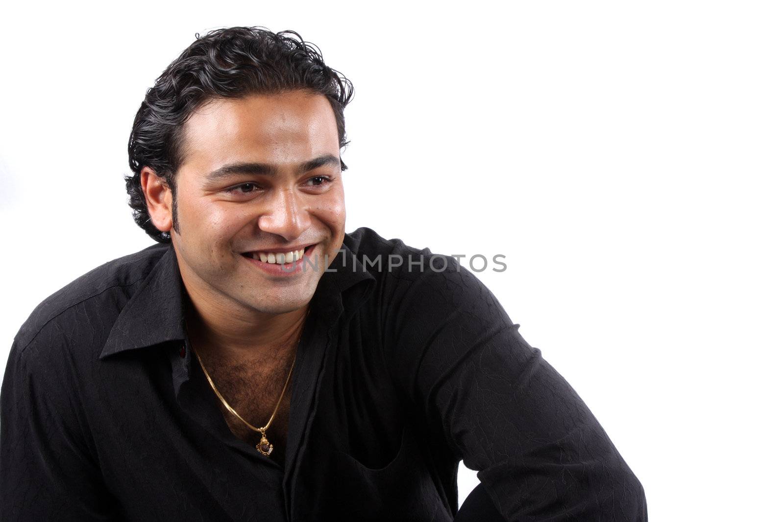 A portrait of a young Indian man wearing a black shirt and gold chain, on white studio background.