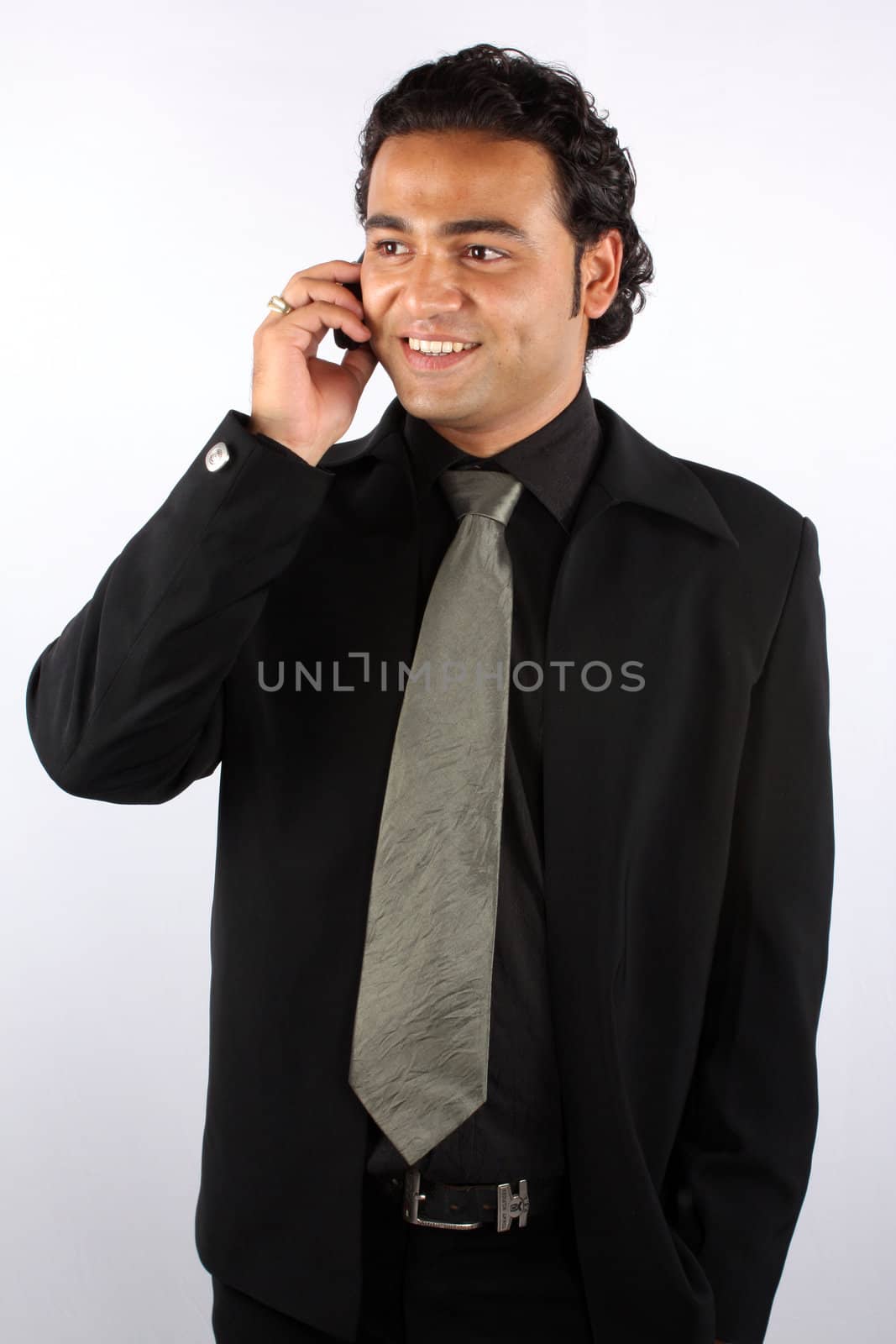 A handsome Indian businessman with a happy expression, while talking on his cellphone.