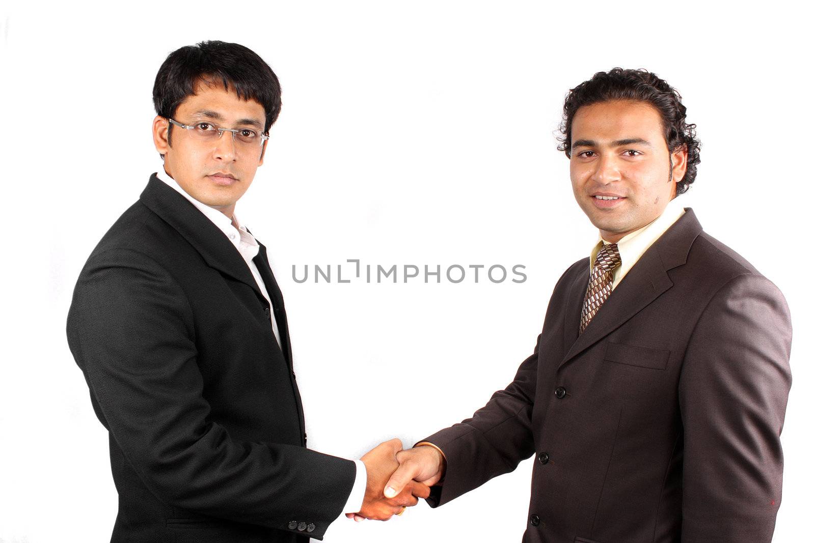 Two young Indian businessmen meeting and shaking hands over a new business deal, on white studio background.