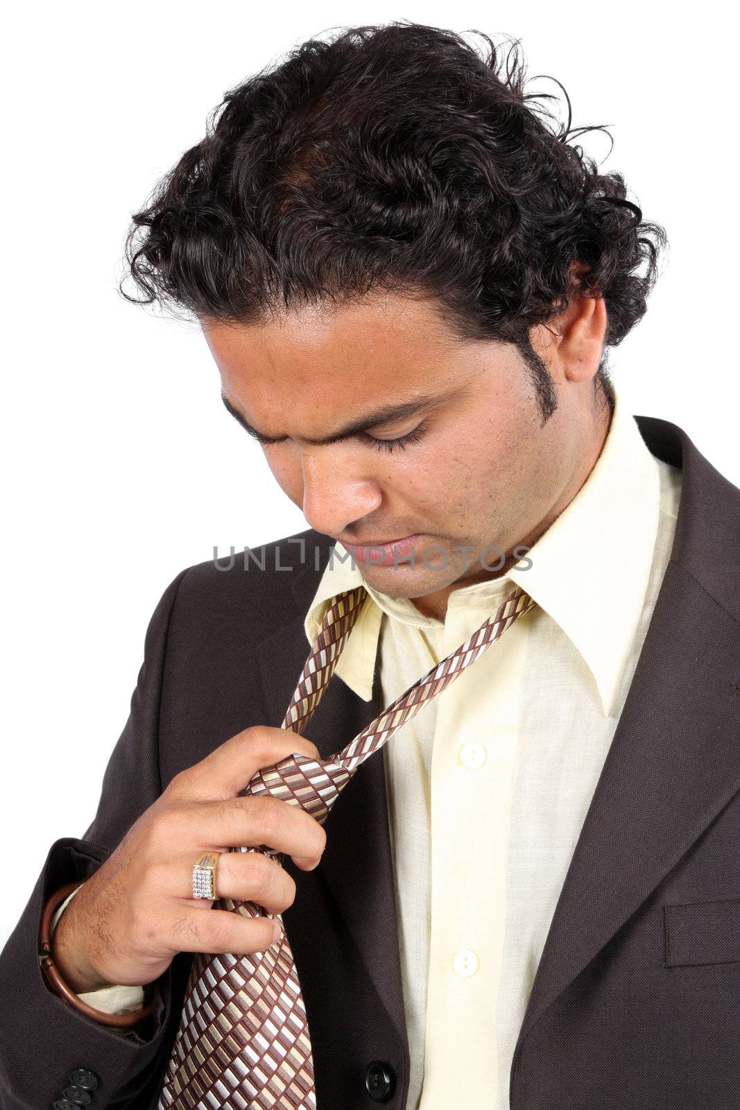 A tied Indian businessman removing his tie, on white studio background.